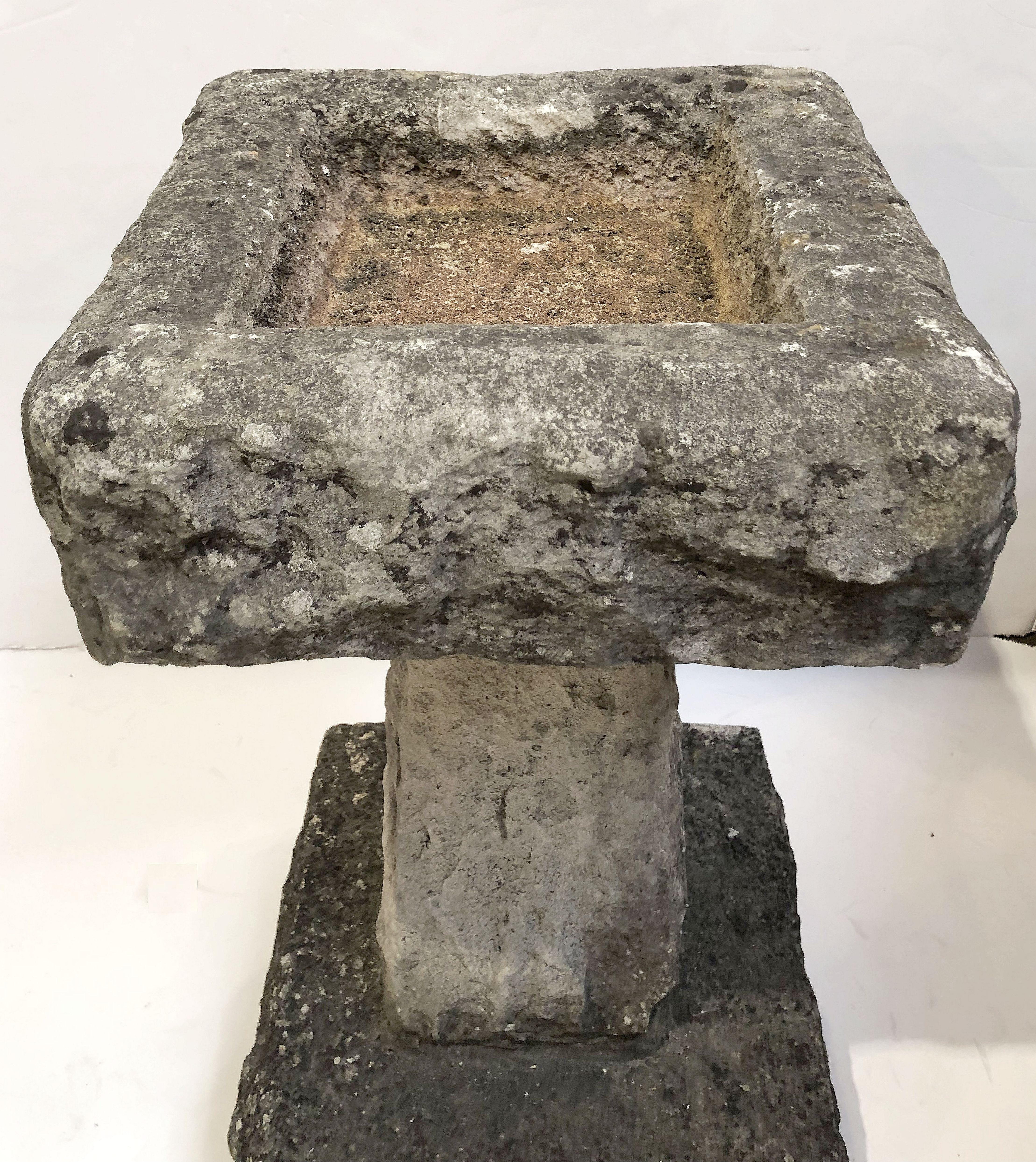 A fine English garden bird bath of carved stone, featuring a square top with recessed area for water, set upon a tapering square column and raised plinth base.

Dimensions: H 24 inches x W 12 1/2 inches x D 12 inches.