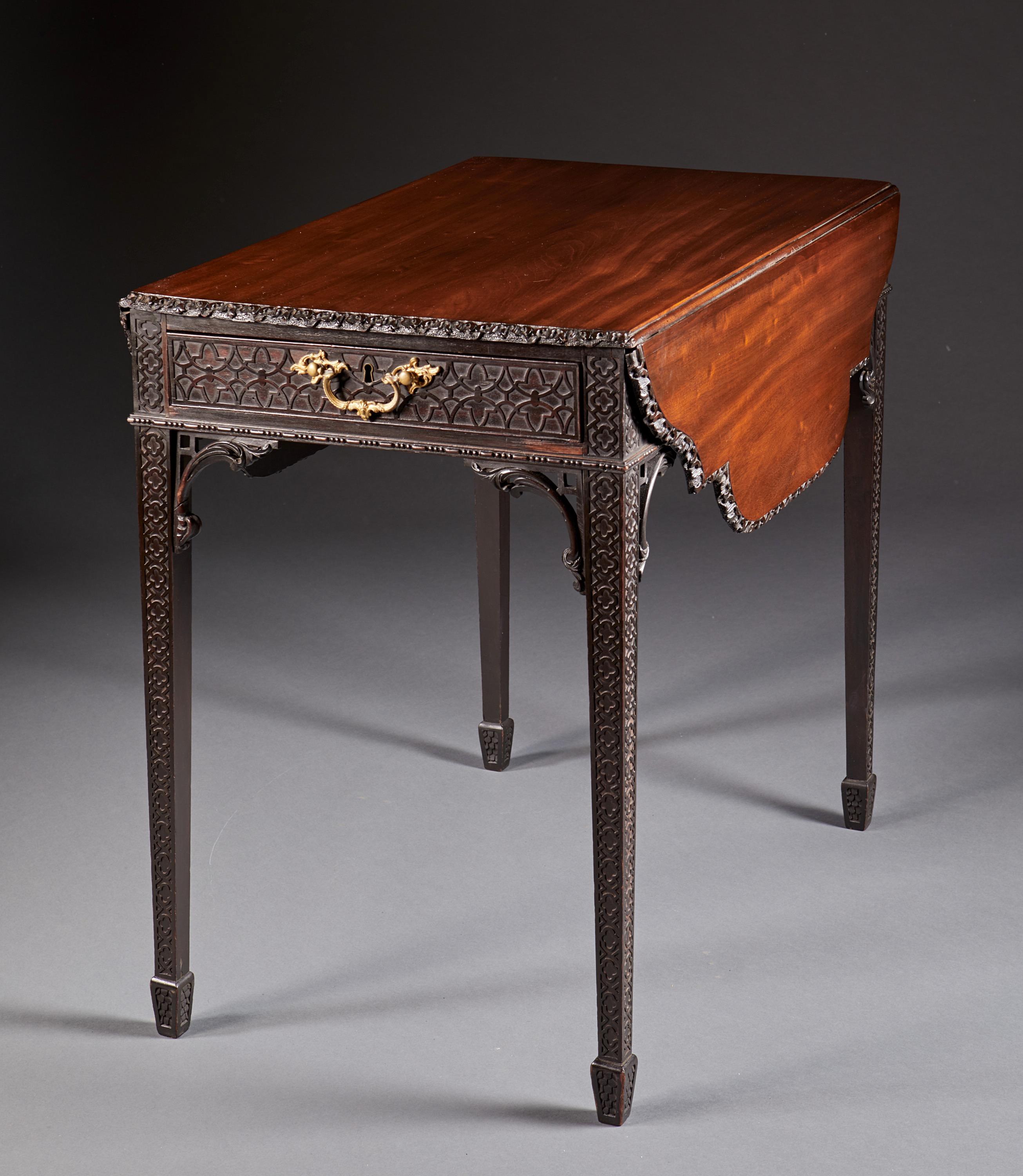 A blind fretwork mahogany Hepplewhite style pembroke table of the finest quality with tapered legs ending in spade feet. The shaped top with deeply carved edge is above a rectangular case with single working drawer with original Rococo gilt