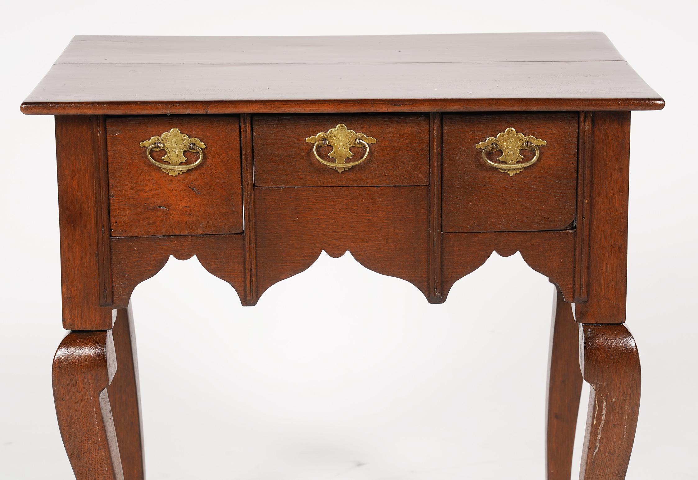 This unusual petite size Queen Anne style carved mahogany lowboy features a polished top above three drawers with original brasses above a three side configured scalloped apron resting on four cabriole legs ending in faceted pad feet, late 18th
