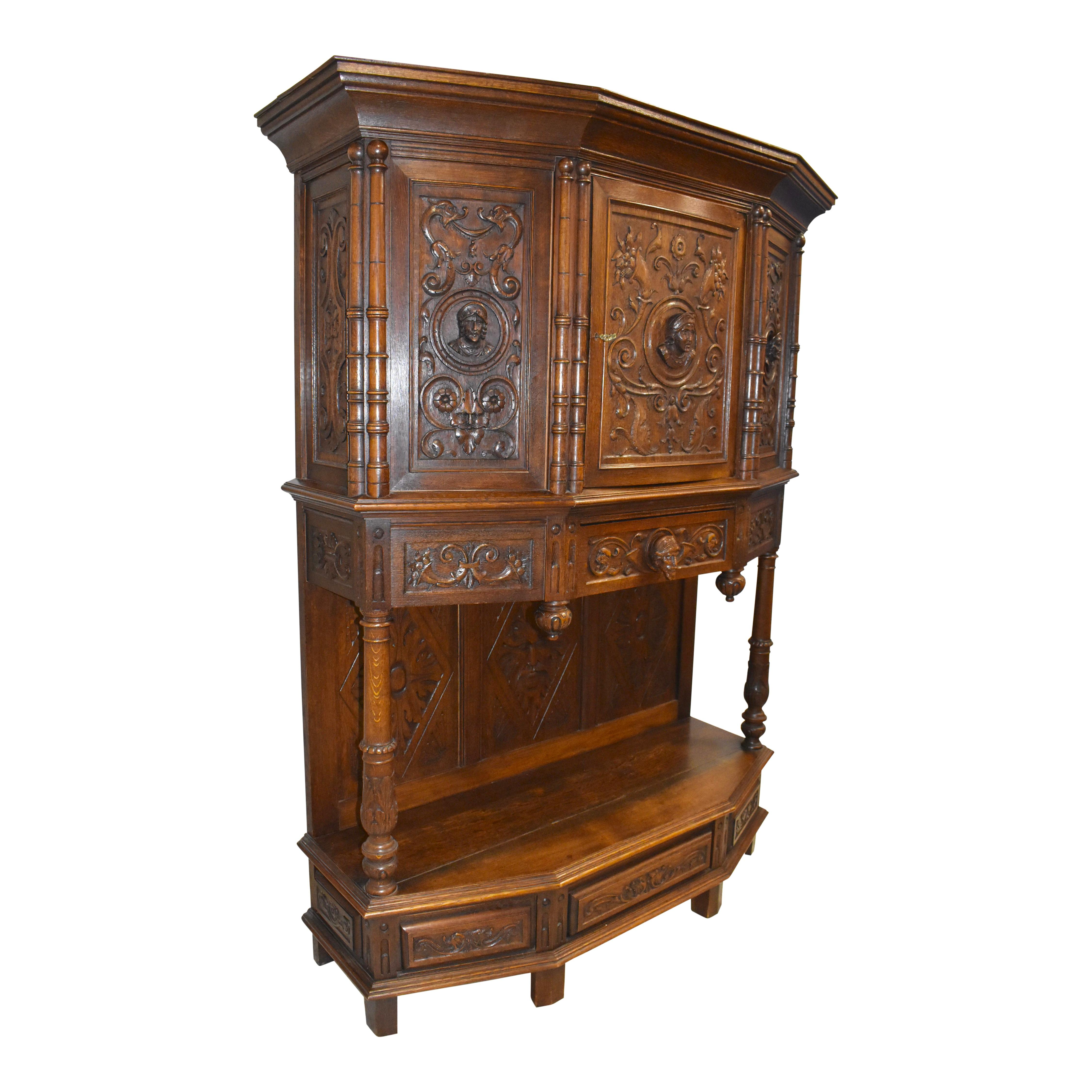 Carved in England in the early-20th century, this handsome breakfront cabinet boasts an imposing appearance with its sharp lines and solid oak construction. The heads of four stately character are carved on the door, side panels, and a center drawer