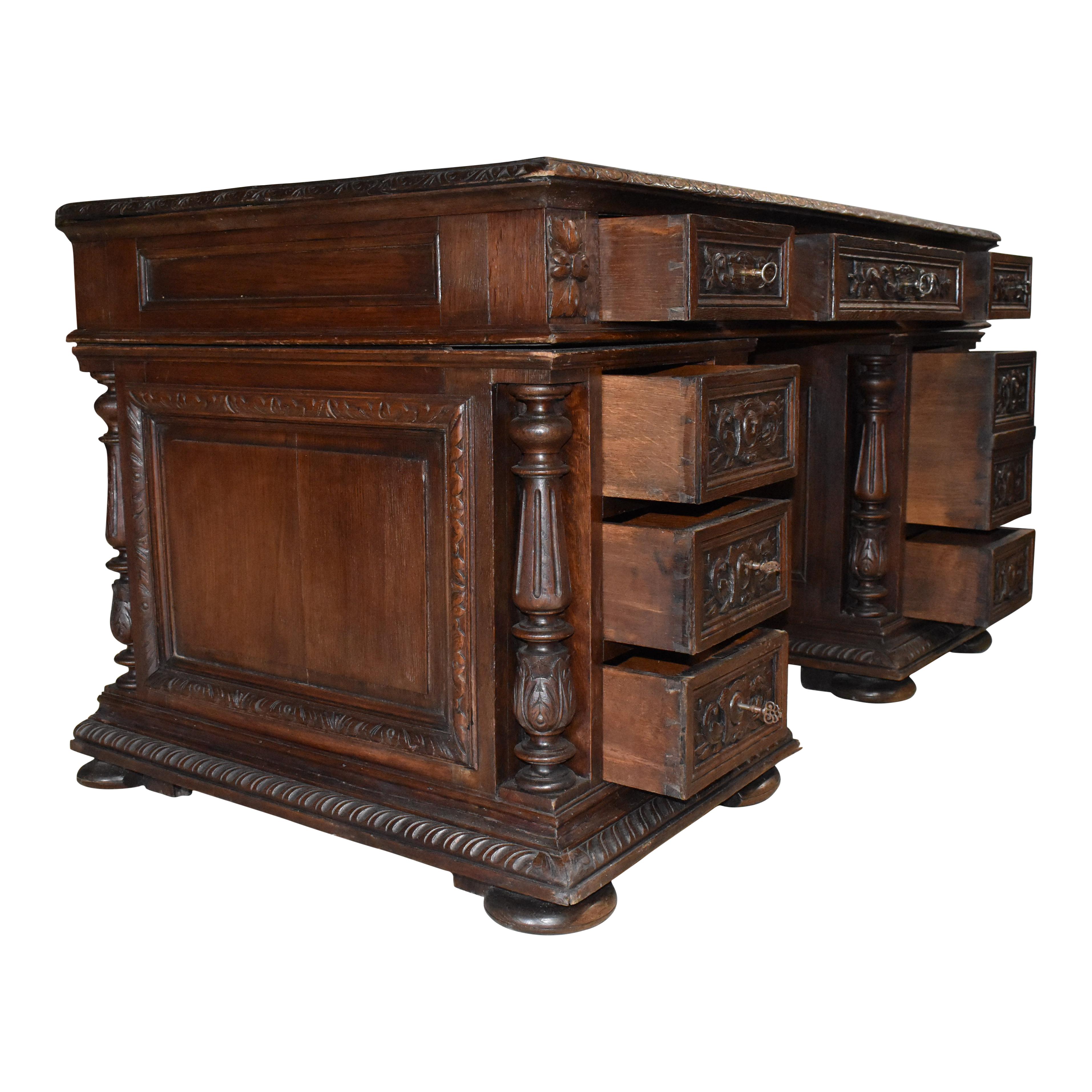 This handsome English desk was created in the late-19th century from European oak and finished with a dark, rich stain. It showcases a rectangular top over a single drawer that is flanked by two smaller side drawers, resting on rectangular