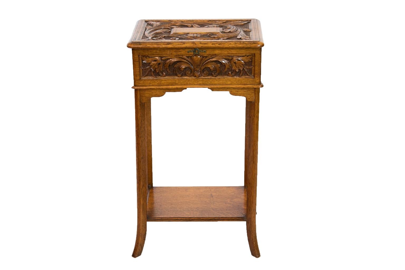 The top of this English oak carved oak lift top side table is carved with floral arabesques and a center raised panel with ebony and boxwood barber pole inlay. The outer edge of the top is also inlaid with similar barberpole inlay on a larger scale.