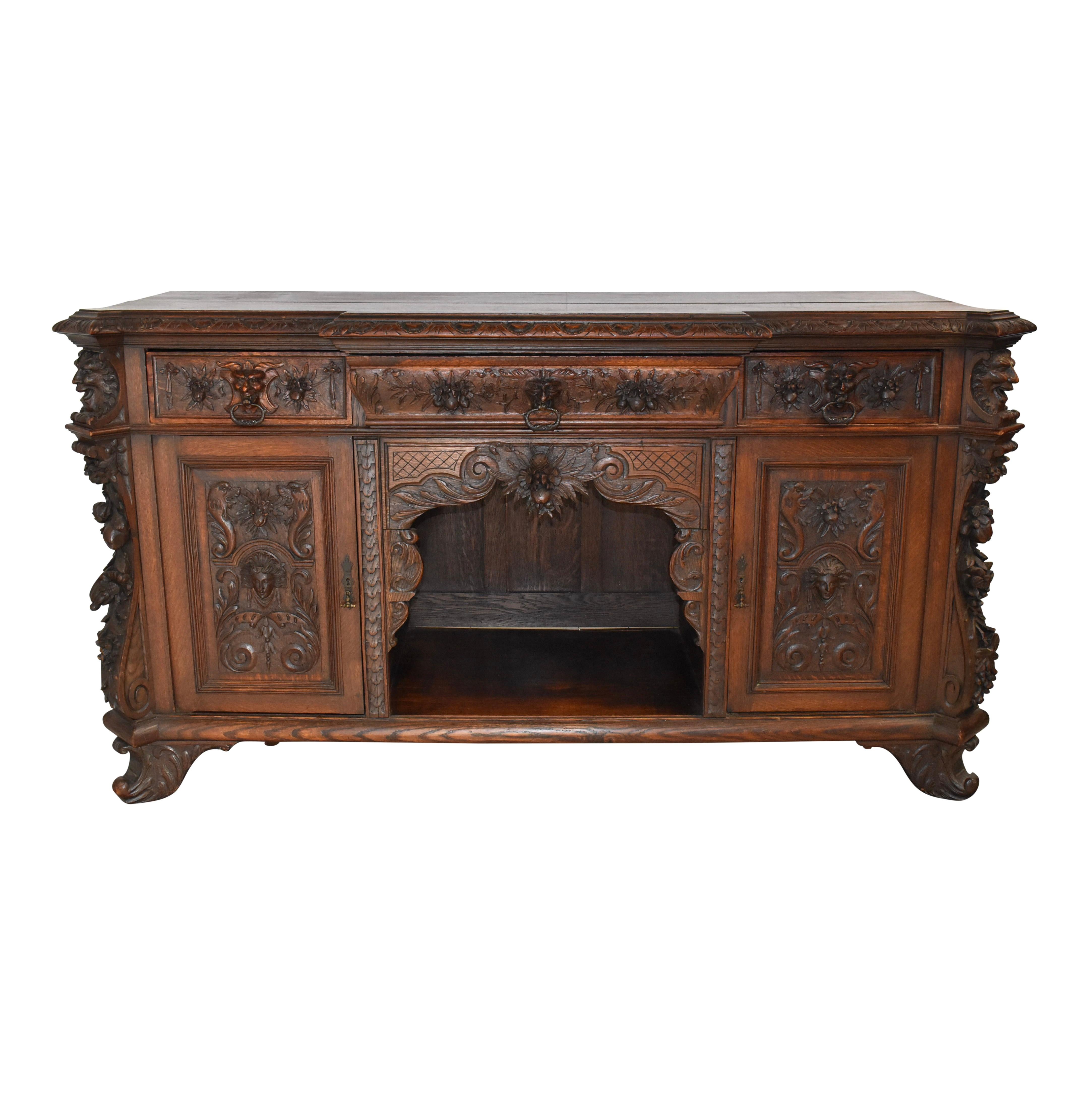 Crafted from beautiful European oak and finished with a dark stain, this Late Victorian sideboard from England showcases elaborate carvings and generous storage. The sideboard features a beveled, breakfront top with modified egg and dart trim and