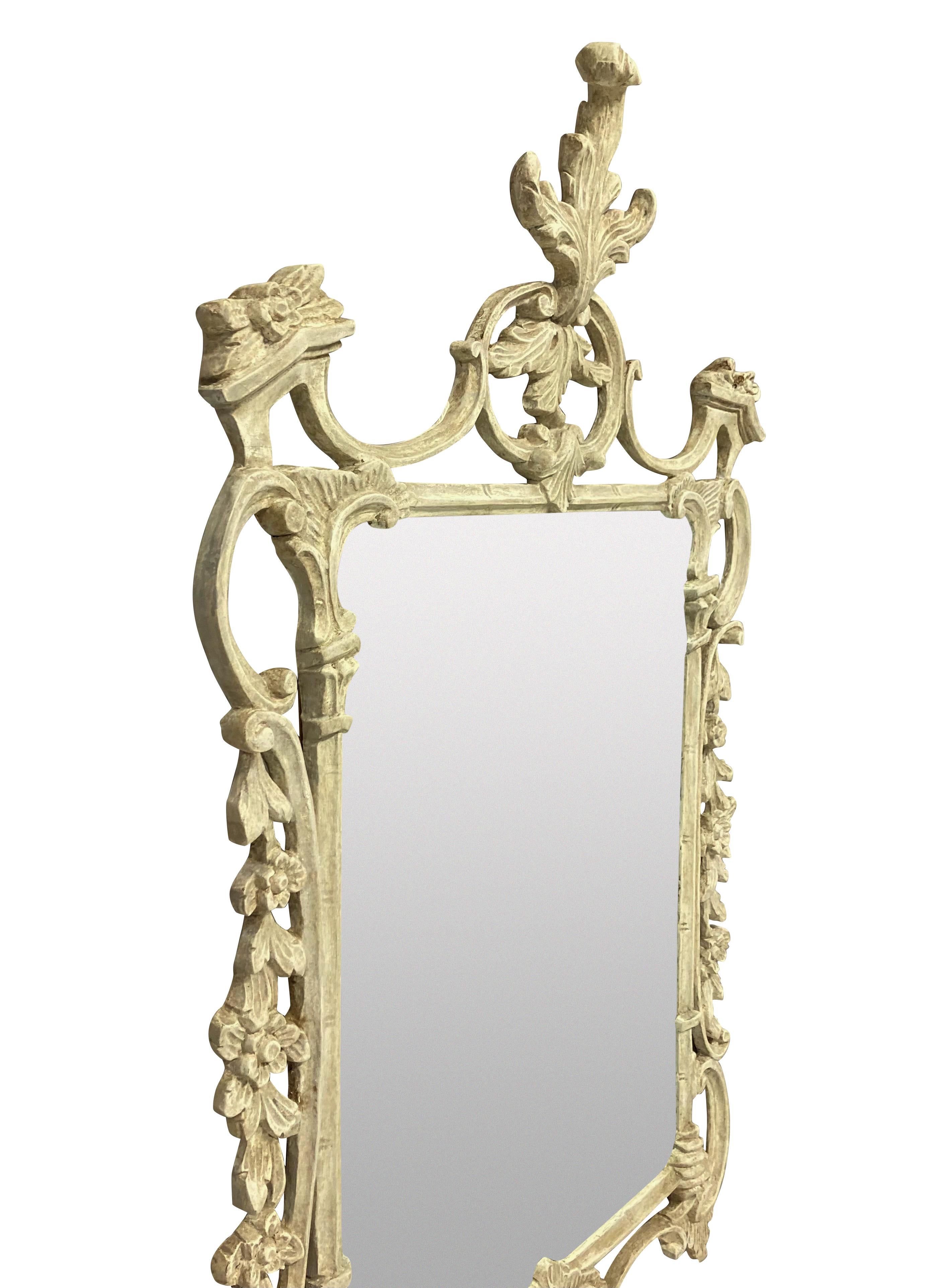 An English finely carved and painted Chippendale style mirror, in an ivory colour, with a later mirror plate.