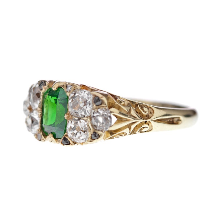 An unexpected rendition of a style popularized over 100 years ago: 18 karat yellow gold classic English carved band with a 2 carat tsavorite garnet center and old European- and rose cut diamond accents totaling 1 carat. This style is easy to wear,