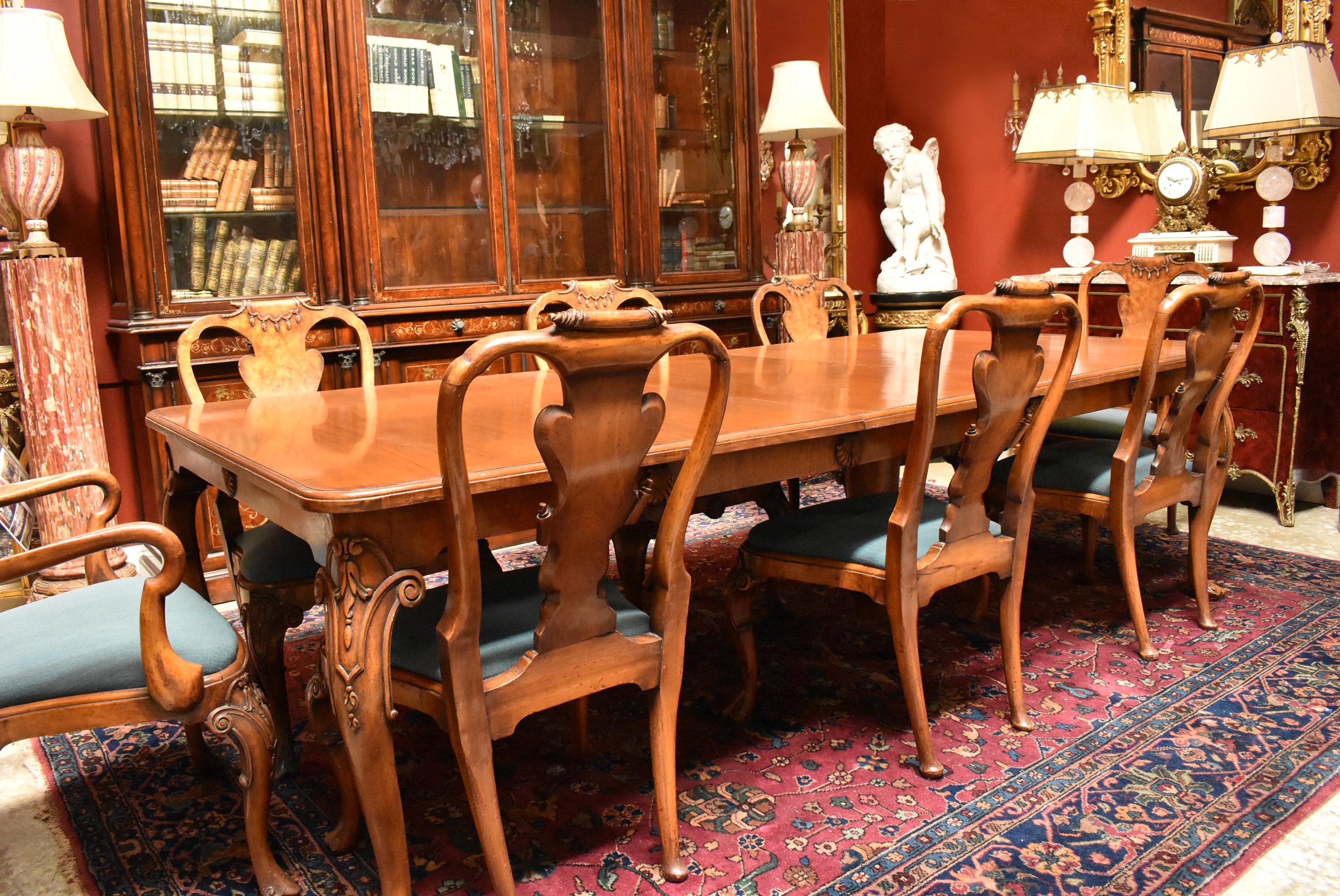 Exquisite large 19th century English George II style finely carved walnut 13-piece dining set with 2 armchairs, 10 side chairs, and large dining table.
The beautiful rectangular moulded veneered top is over a conforming frieze carved in a shell