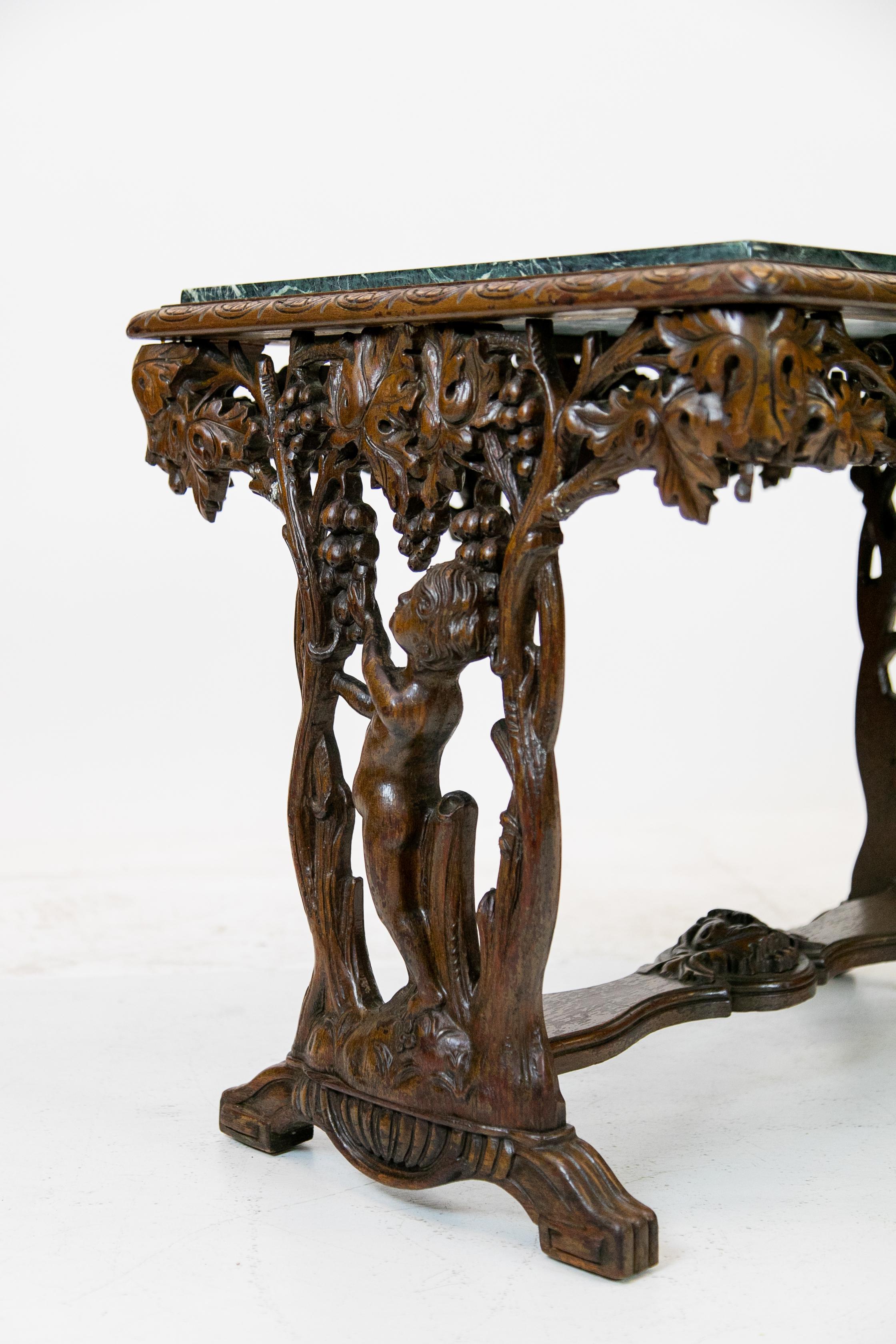 English carved walnut marble-top table, with Verde marble top above carved grape vine and allegorical figures in base.