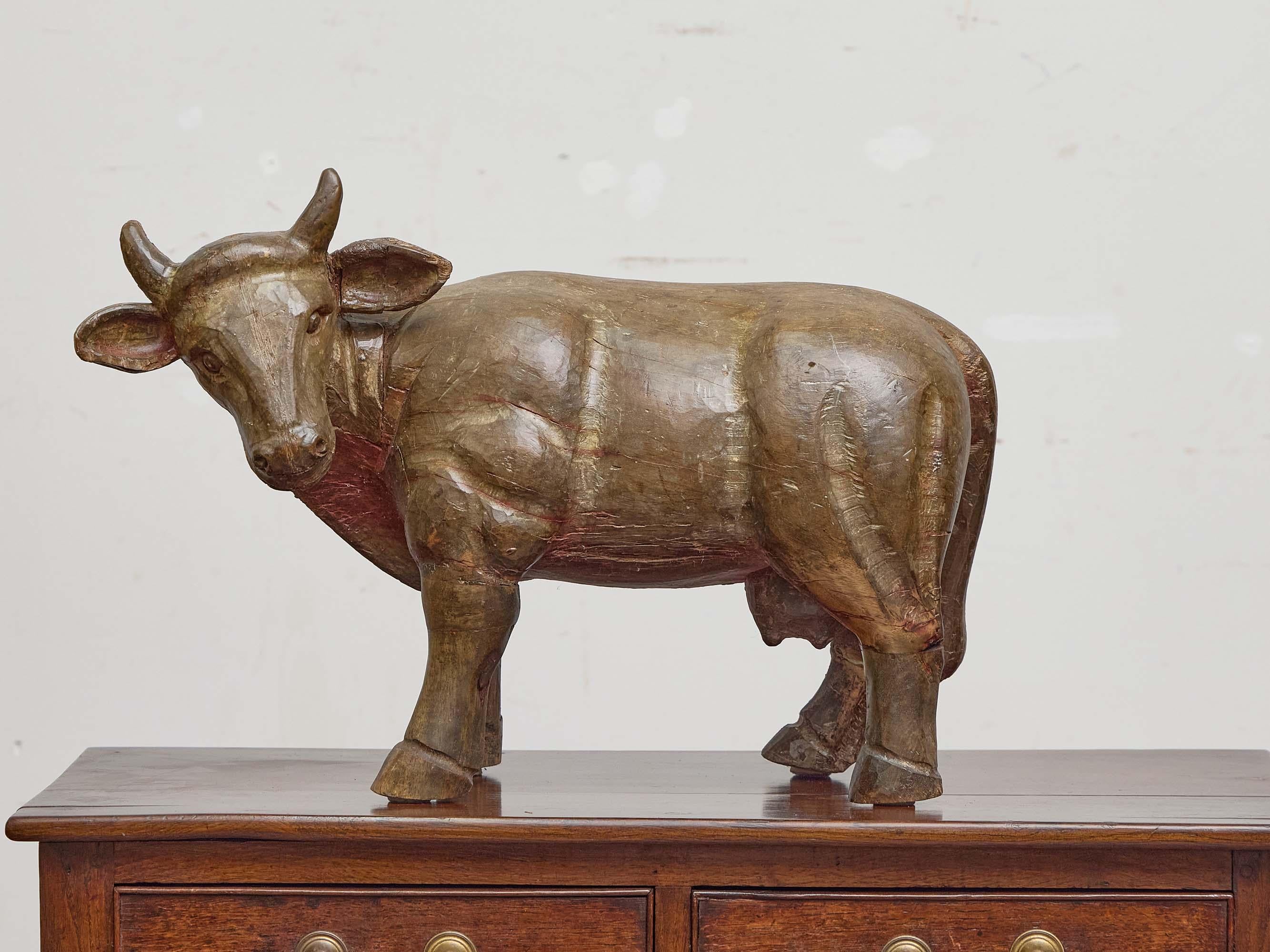 A rare and well-proportioned English carved wood cow, circa 1880, retaining traces of its original painted finish. Crafted with the naïve charm characteristic of 19th-century folk art, this hand-hewn figure captures the essence of the dairy cow with