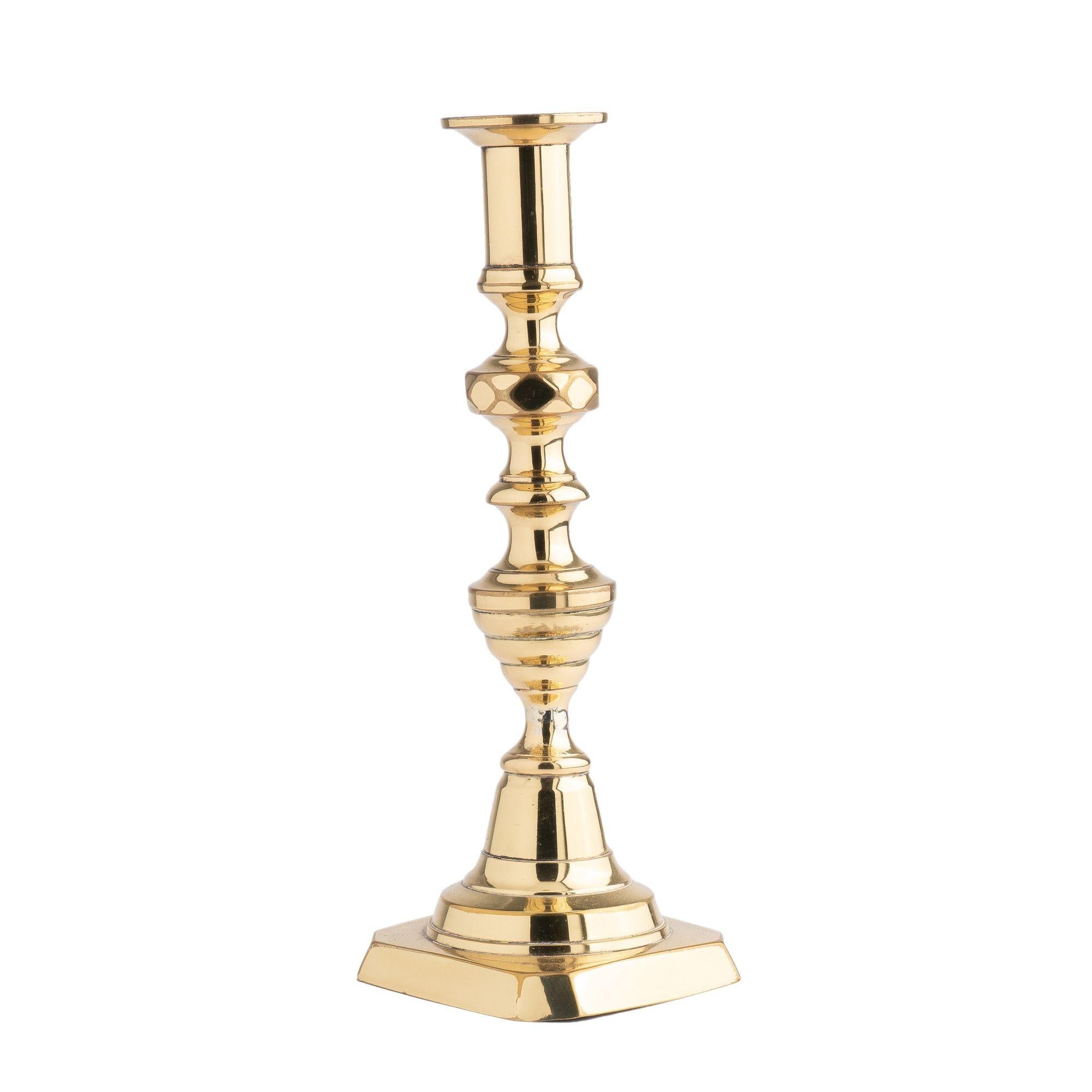 English hollow core cast brass inverted beehive candlestick. The elongated urn form candle cup with bobeshe rests on a short pedestal above a diamond faceted knob. The candle shaft features a waisted interval to an inverted beehive on a conical