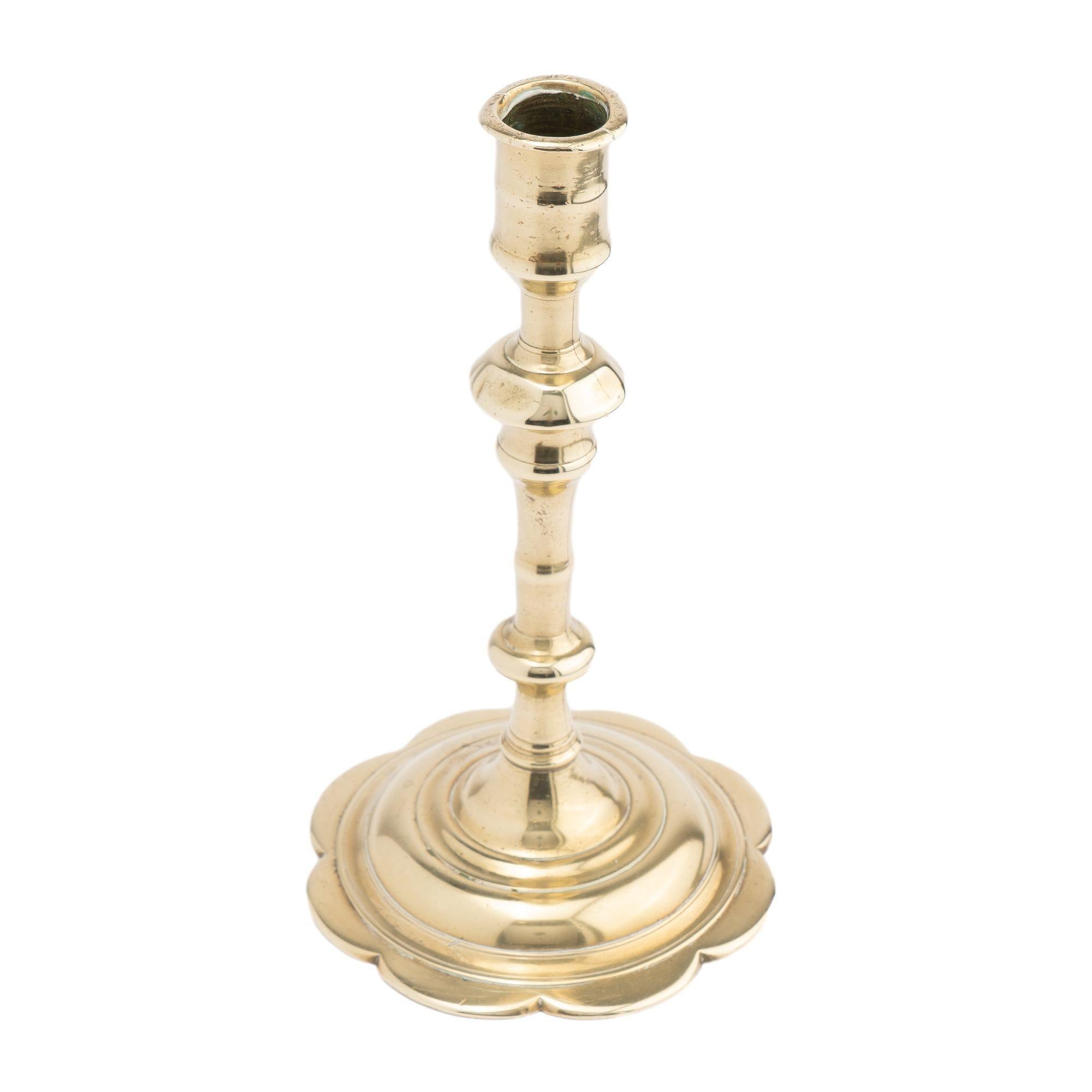 Seam cast brass Queen Anne candlestick with knobbed shaft & candle cup. The casting of the shaft is in two parts, silver soldered together and peened to a domed and scalloped edge base.

Birmingham, England, circa 1760-70.