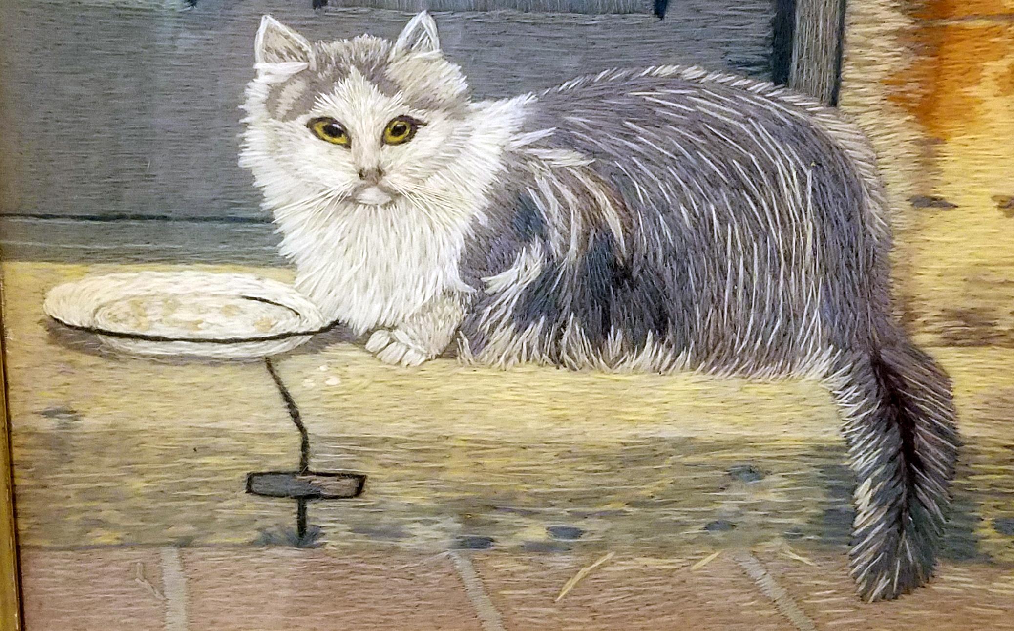 Longhaired gray and white cat woolwork,
circa 1840. 

The unusual and rare woolwork in lovely grays and browns depicts a long-haired gray and white cat crouched on all fours sitting by a bowl of food on the stoop of a doorway. The cat looks