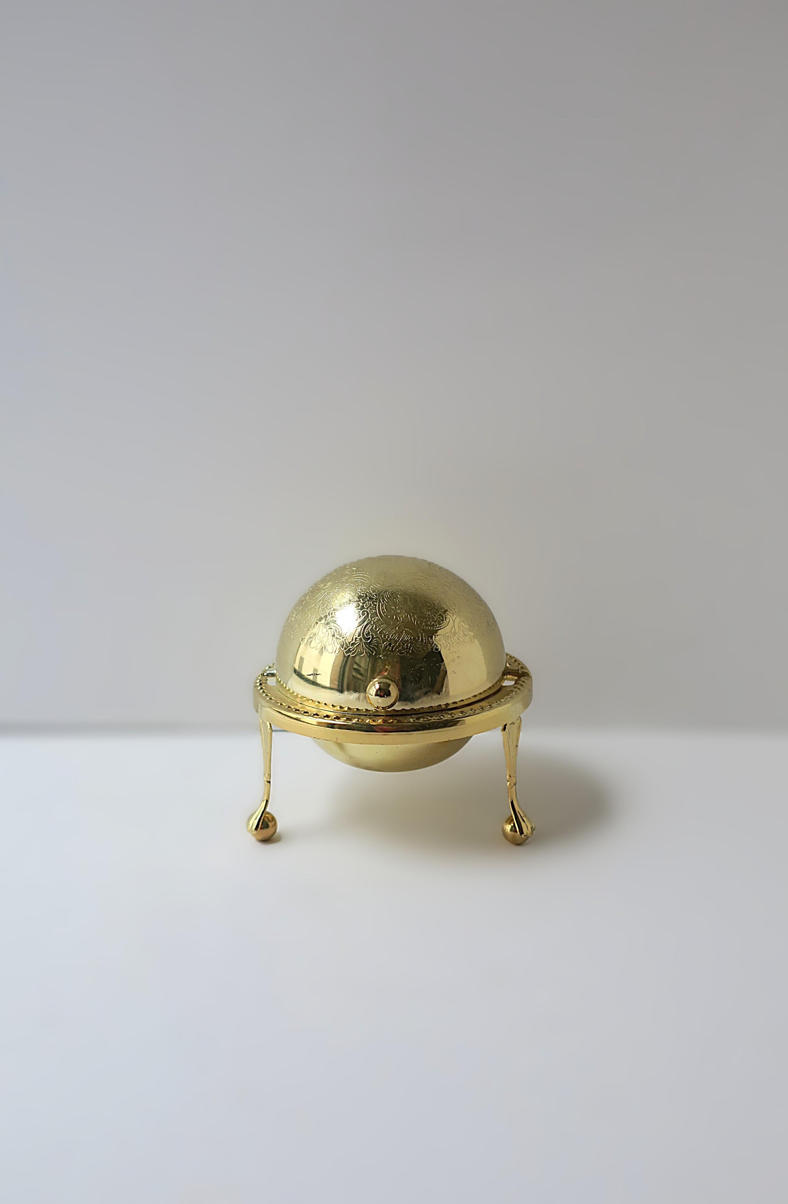 An English gold metal over silver plate and glass caviar covered dish with lion paw feet, in the Empire style, circa mid-20th century, England. Piece has an easy rolltop lid with cut glass dish insert (ice can be added below dish), finished with