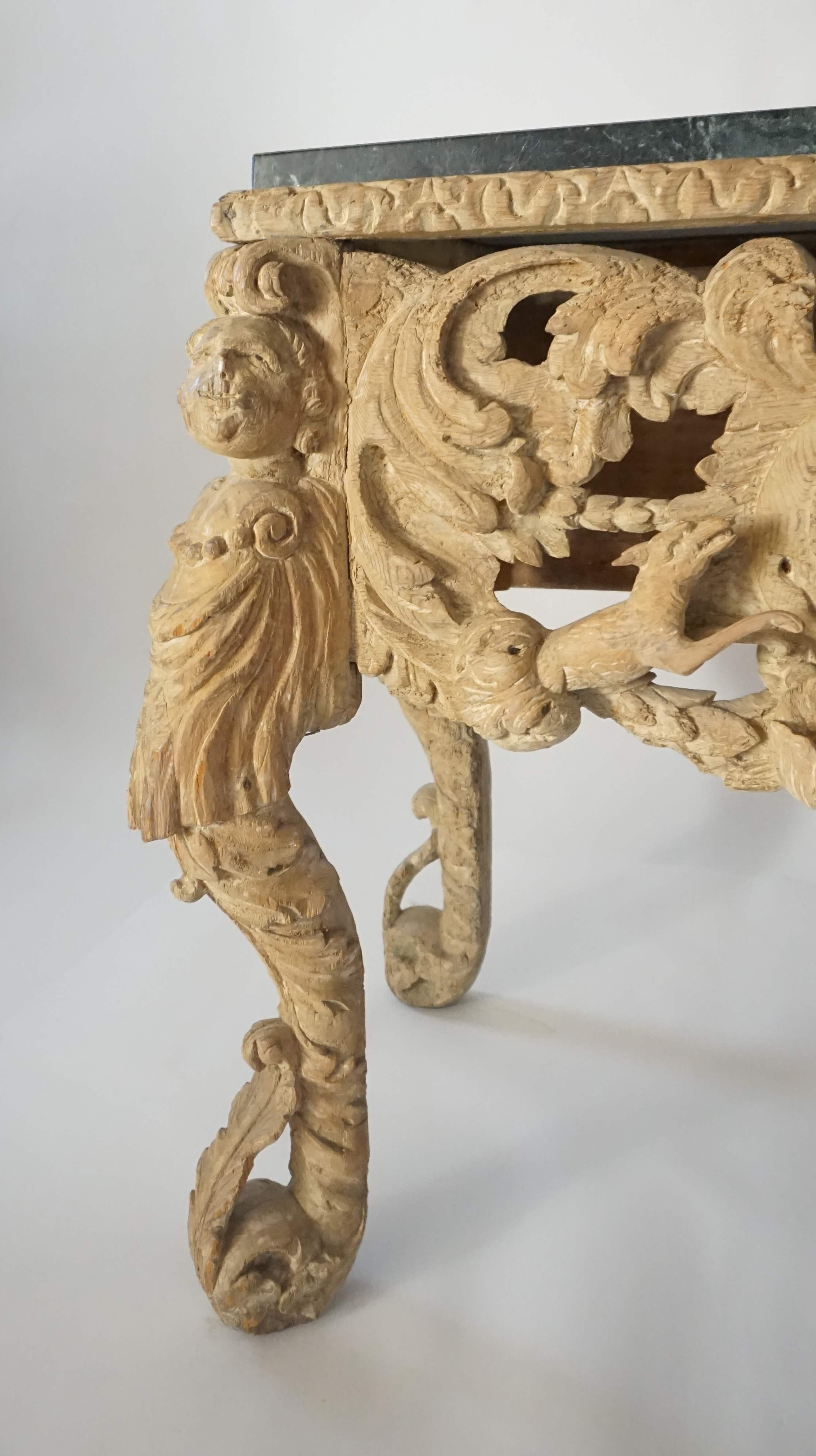 English Charles II Carolean Restoration period console or side table in original lime wash finish on elaborately carved base supported by carved putto and acanthus terms joined on sides by winged putto heads in acanthus aprons; the front with deep