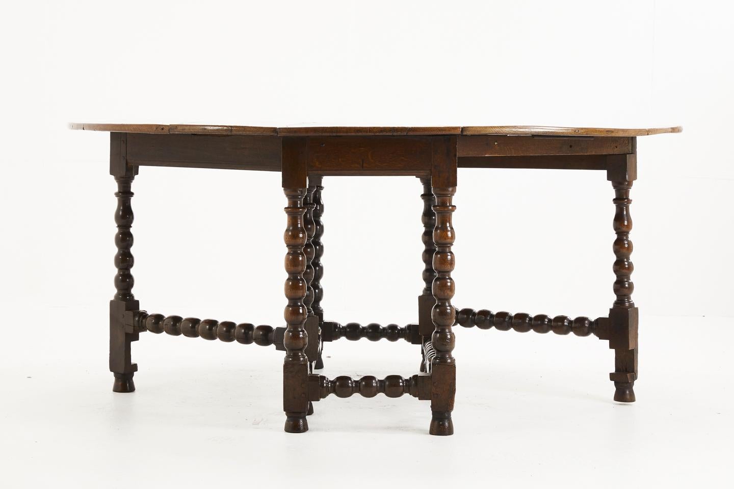 Large 17th century Charles II oak drop leaf table with bobbin turned gate legs. This wonderful table has been restored many times over the centuries. Having very rare and unusual gate leg stabilising-arm beneath, 
circa 1680.

Dimensions when