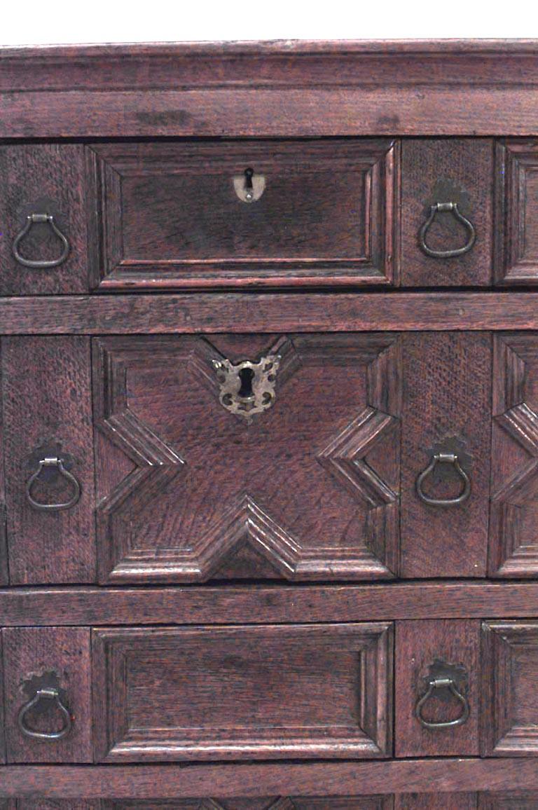 English Jacobean style (17th Century elements or later) oak chest of drawers with 4 geometric fronted drawers above an apron on bracket feet.
