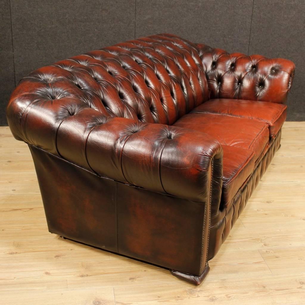 English sofa of the second half of the 20th century. Chesterfield sofa finished for the centre, covered in leather, of fabulous decor and in beautiful patina. Good comfort couch equipped with three cushions. It does not present splits or breakages.