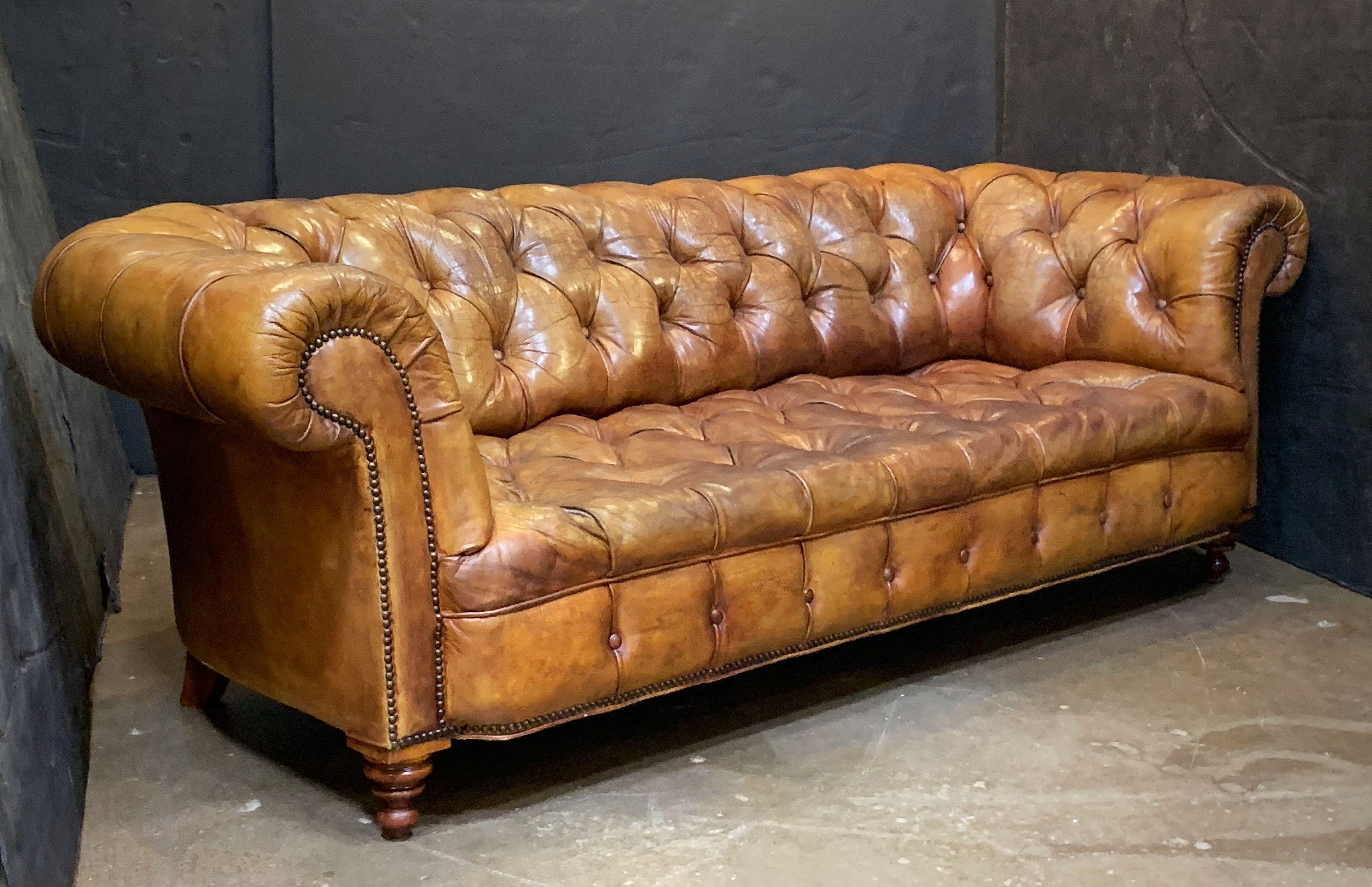 A fine, comfortable English Chesterfield sofa in vintage brown or tobacco leather featuring button-tufted back, arms, and seat, and beaded-nail trim design, resting on turned feet.

The Chesterfield sofa is a Classic, synonymous with English