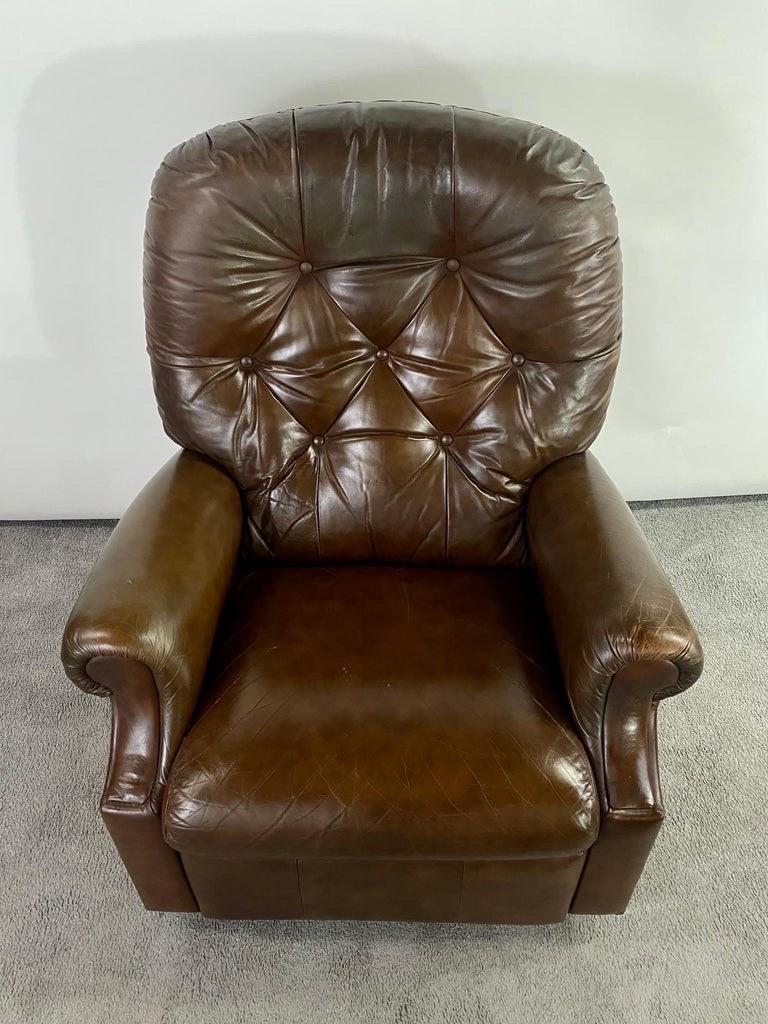Questa squisita poltrona club reclinabile incarna l'intramontabile eleganza del design tradizionale inglese, che si fonde perfettamente con la funzionalità della metà del secolo scorso. Rivestita in una ricca pelle marrone pieno fiore, la sedia