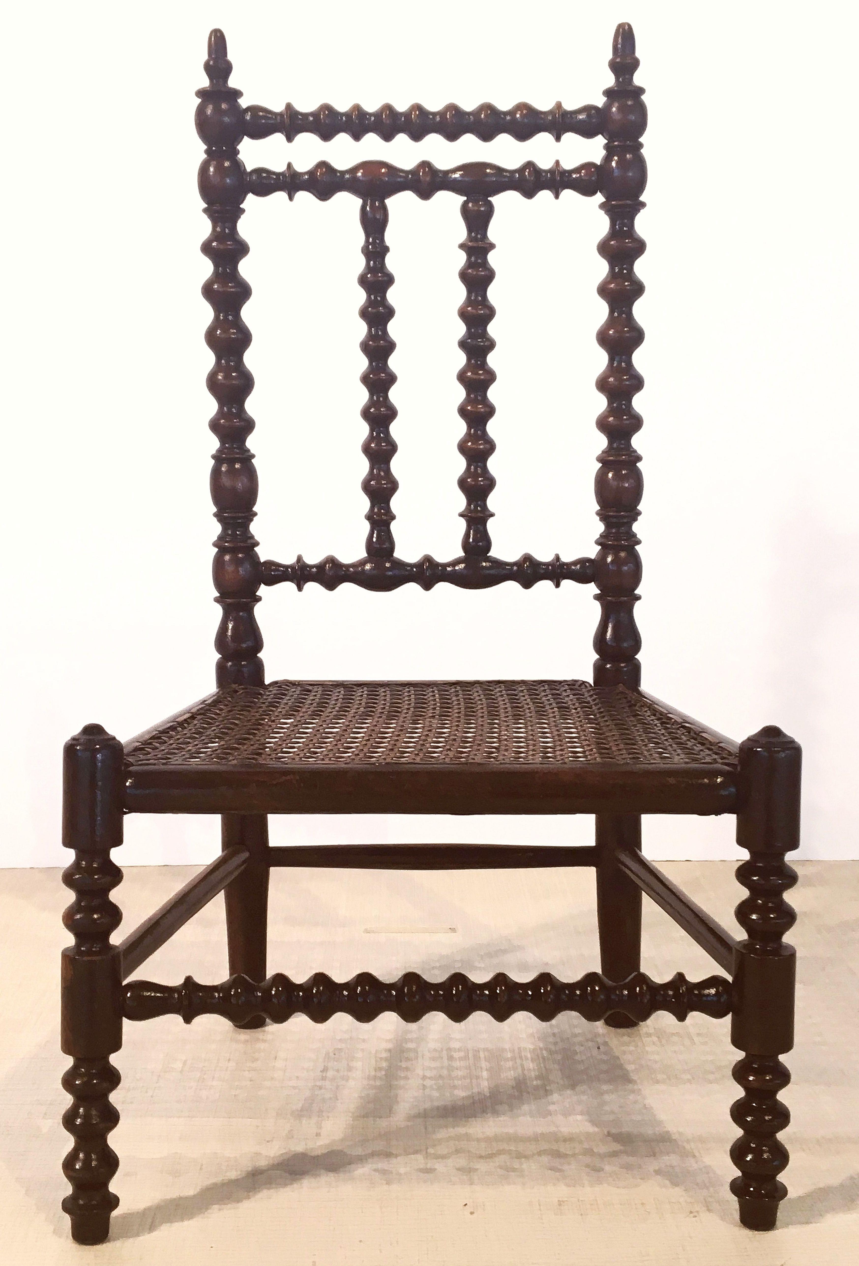 A fine English child's chair from the Victorian era, featuring a bobbin turned frame and bergere caned seat.