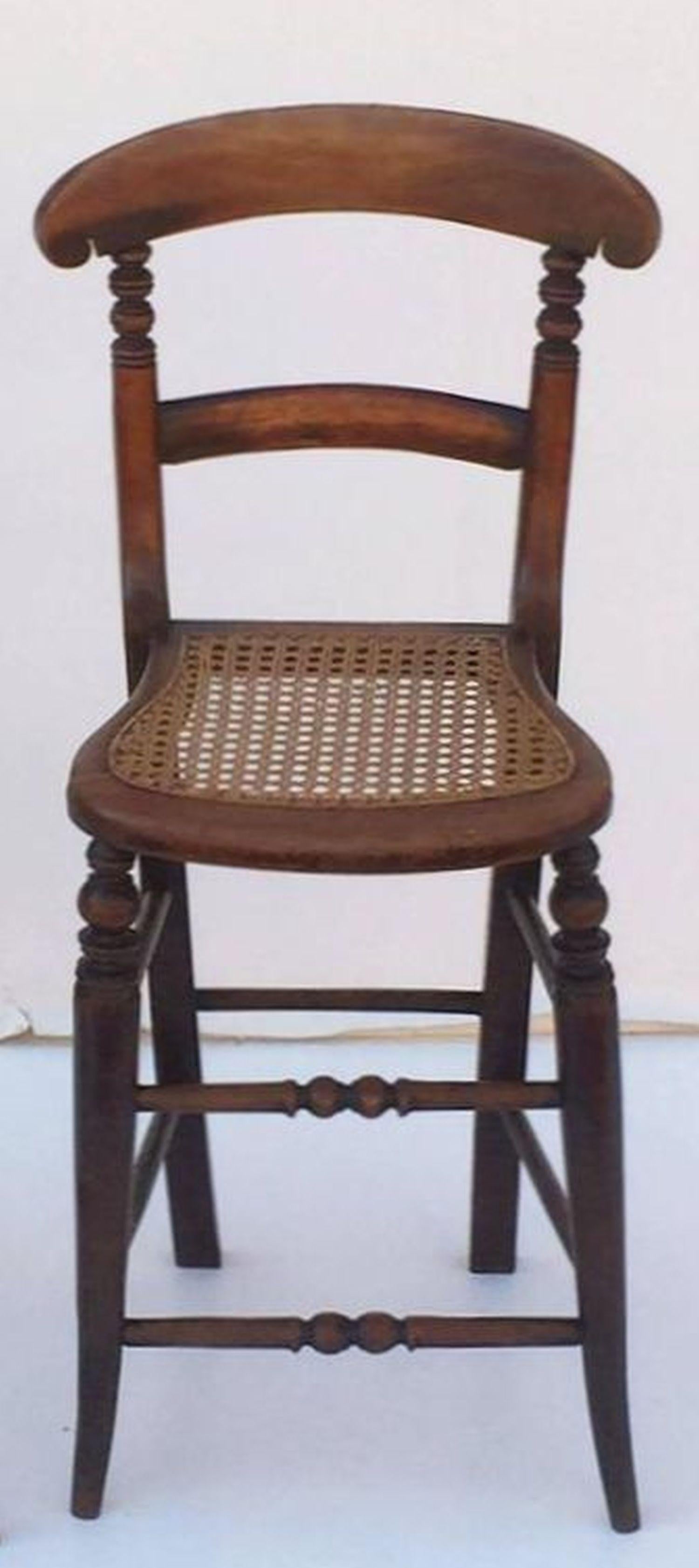 A handsome English children's correction chair from the Georgian era, featuring a bowed back and turned supports with Fine patination to the wood, and a shaped caned seat in excellent antique condition.

These deportment or correction chairs are