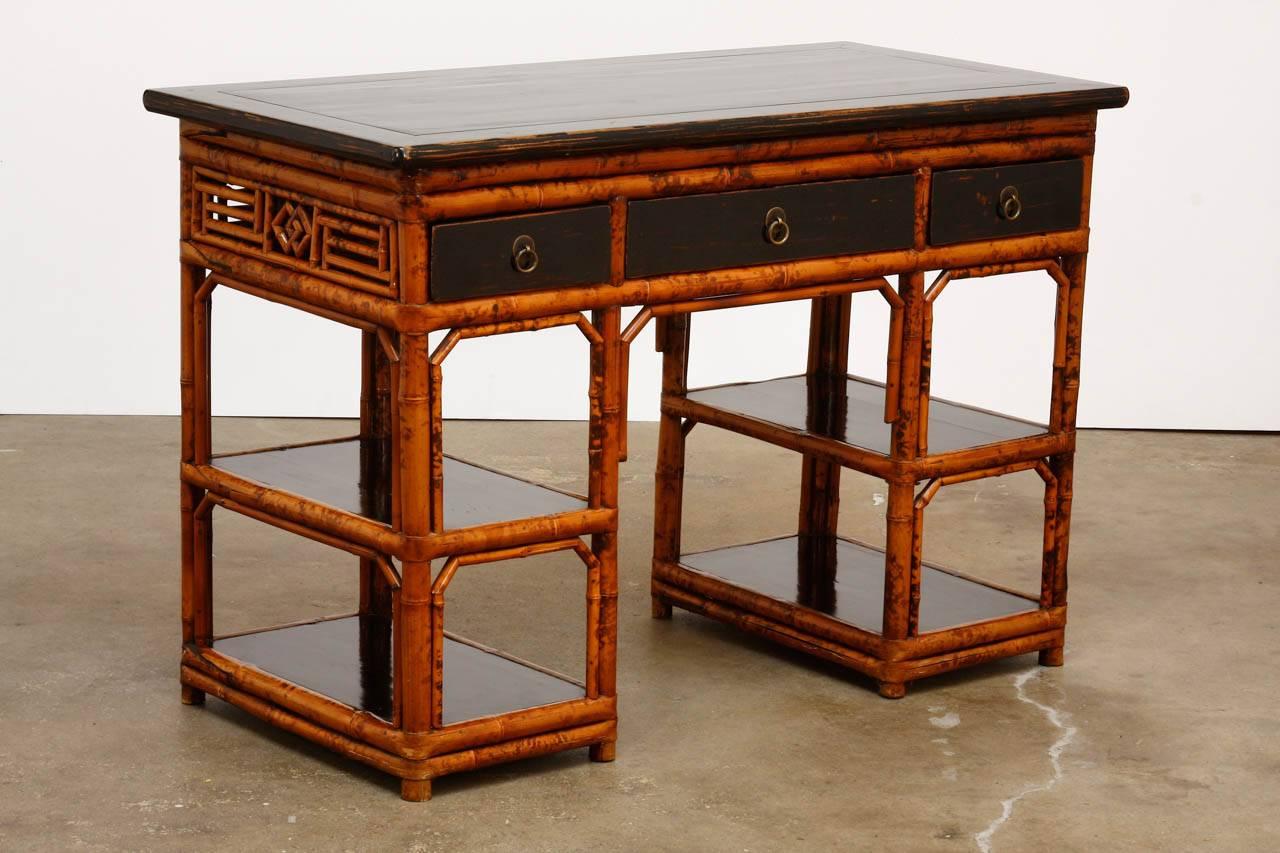 Fantastic English Chinese Chippendale style bamboo desk featuring a case made of rich tortoise shell bamboo. Each side pedestal has two display shelves with a black lacquer bottom. The case is fronted by three wooden drawers also finished in black