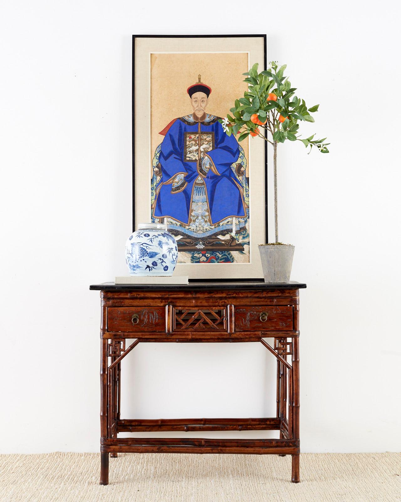 Fantastic bamboo table or writing table desk made in the English Chinese Chippendale chinoiserie taste. Features a case made from bamboo decorated with open fretwork geometric designs. Fronted by two wooden storage drawers with brass ring pulls and