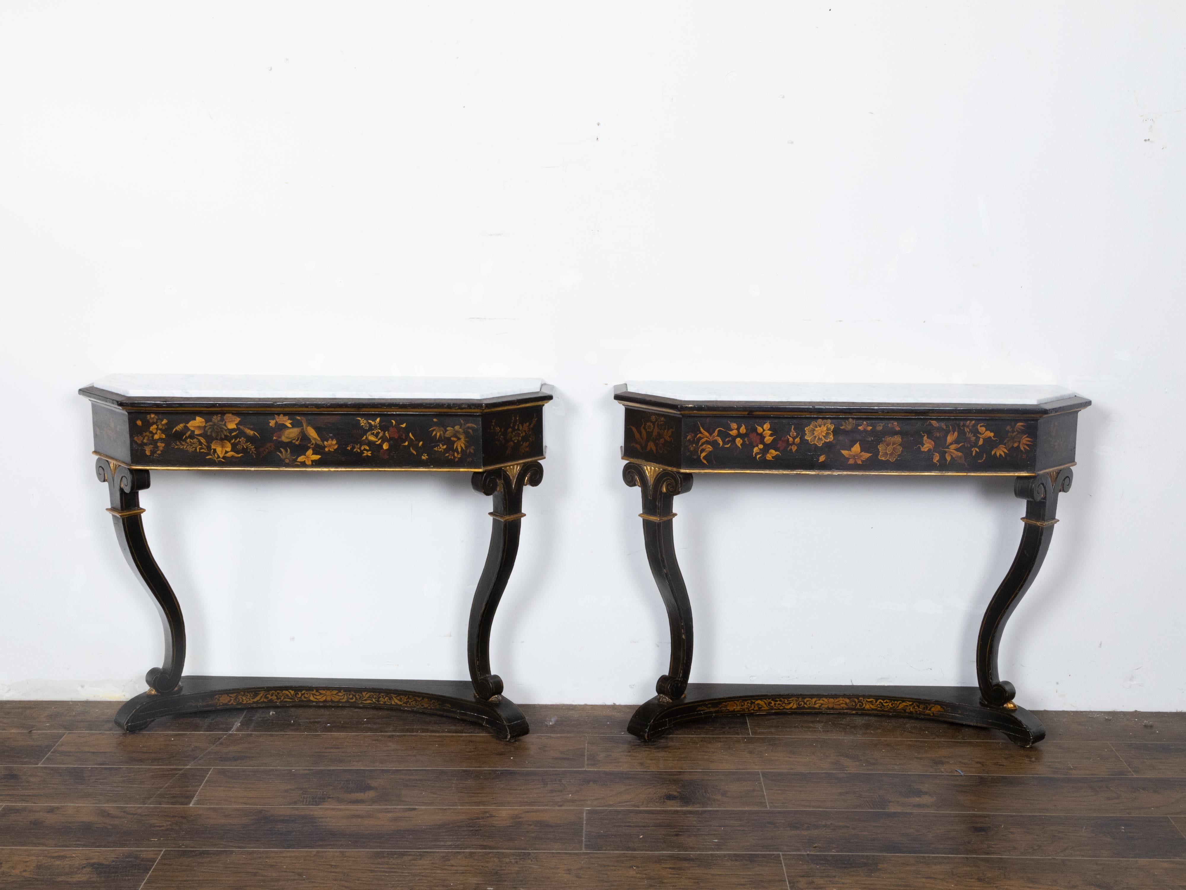 A pair of English Chinoiserie black and gold console tables from the 19th century with white marble tops. Embrace the exquisite fusion of East and West with this pair of English Chinoiserie black and gold console tables from the 19th century, pieces