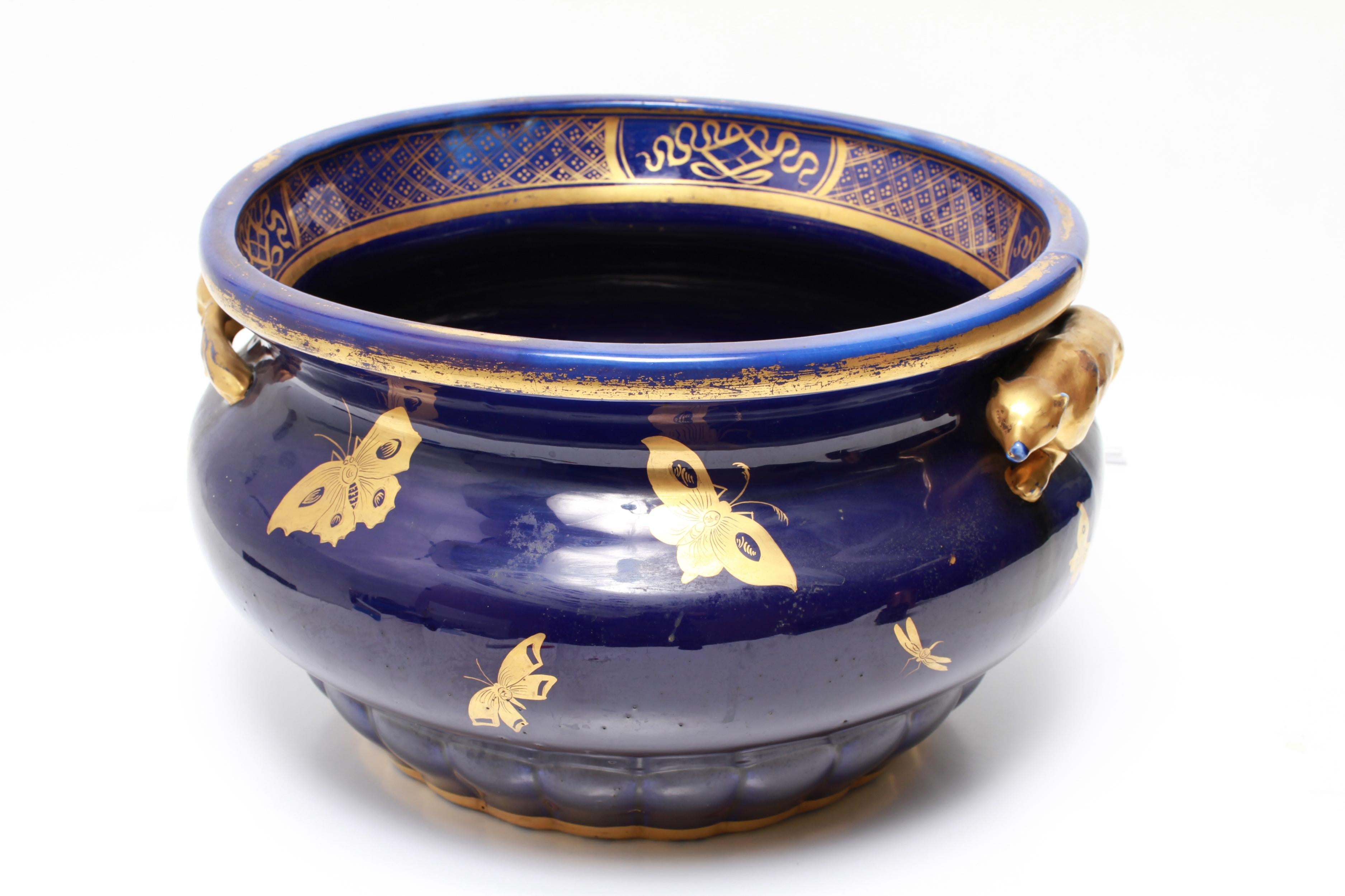 English Chinoiserie porcelain jardiniere, possibly made by Spode, in glazed cobalt blue ground and hand-painted with gilt flowers and insects, with two applied gilt fox handles. Numerous stilt marks to the underside, some glazed. Some wear and
