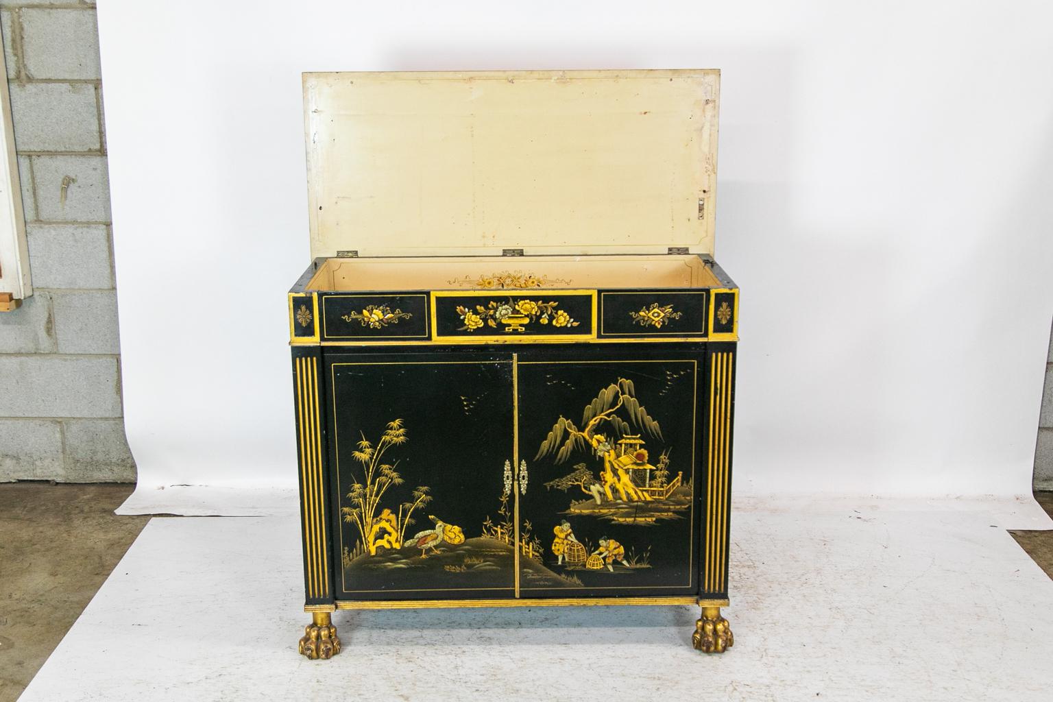 This cabinet has gold chinoiserie decoration with red and green highlights. The frieze has panels painted with an urn with flowers in the center and musical and scroll themes on the side panels. The right-side panel has a bird perched in a floral