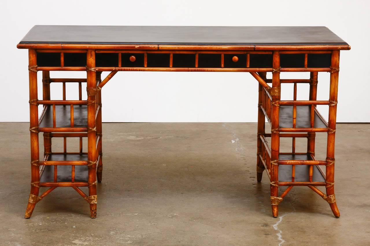 Stunning bamboo writing table desk by Milling Road for Baker made in the English chinoiserie taste. Features a large desk top supported by two pedestals each having two galleried shelves or display areas. Fronted by one large drawer with a