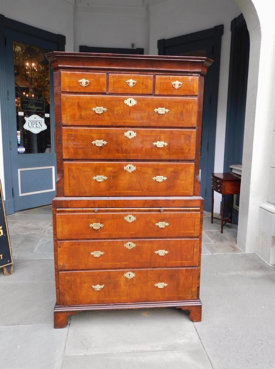 Cassettone inglese Chippendale in radica di noce satinato intarsiato a fasce di piume, con cornice intagliata sul bordo, tre cassetti superiori, sei cassetti inferiori graduati con serrature interne, colonne scanalate affiancate con angoli smussati,