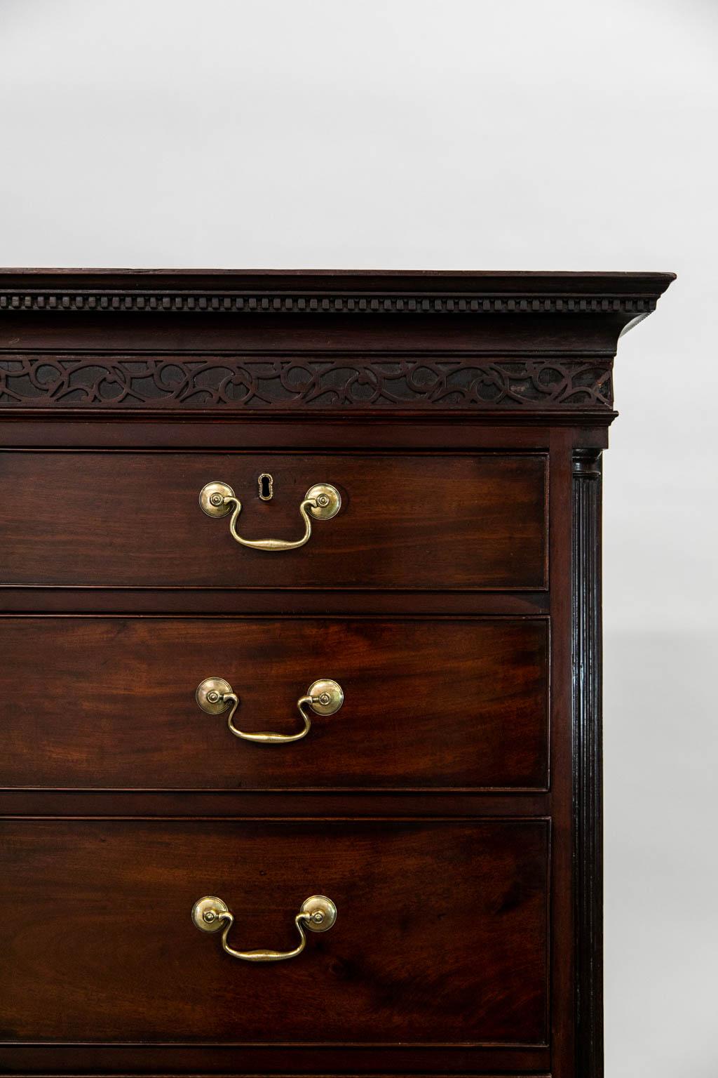 The cornice of this chest on chest has a diminutive dentil and egg and dart cornice with blind fretwork that extends on all three sides. The top section has a fluted quarter column with a blind fretwork plinth base. There are shrinkage separations