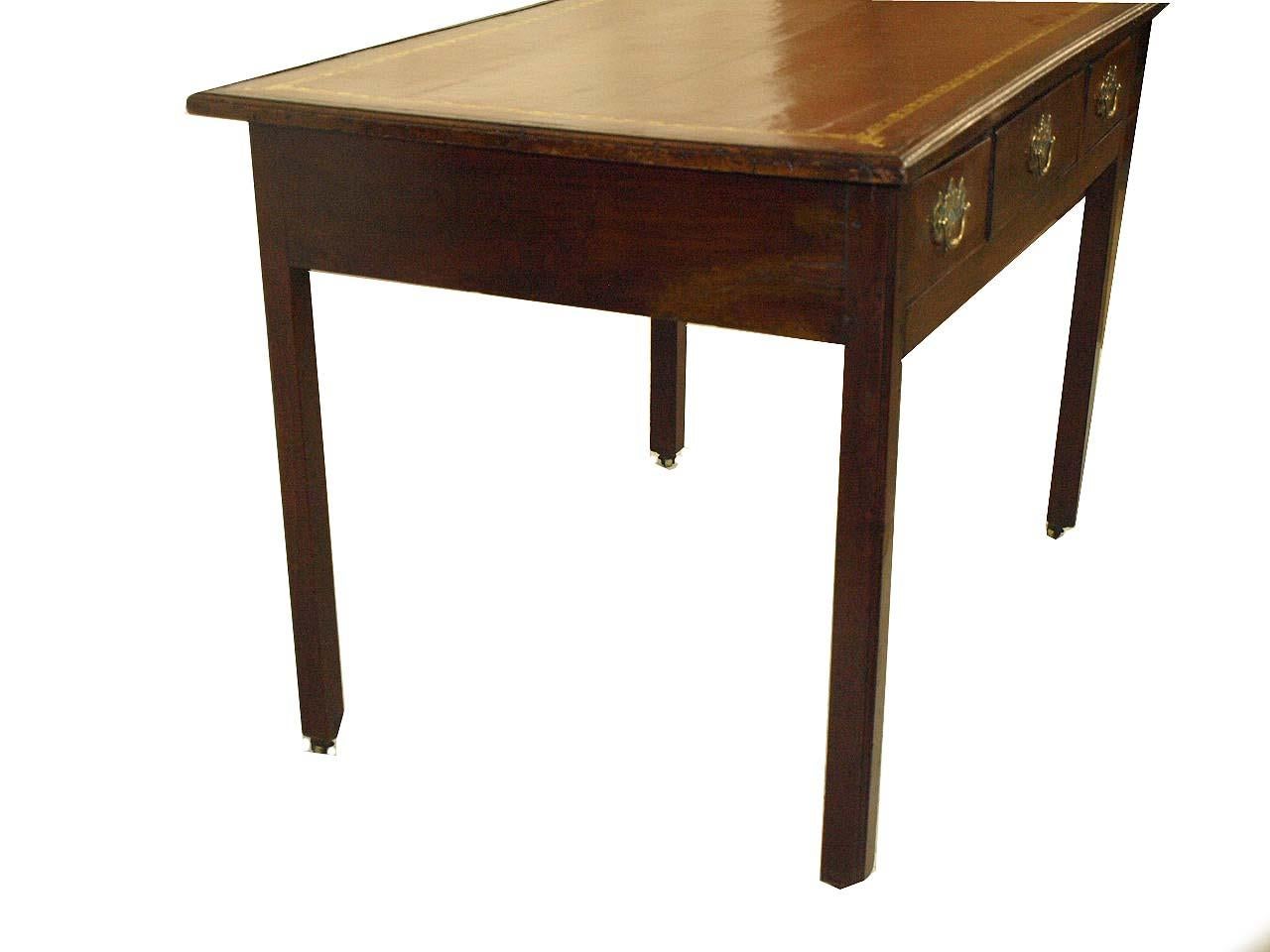 English Chippendale mahogany leather top table, the three drawers with mahogany secondary wood and retaining their original open fretwork brass pulls. The straight legs with molded front outer edge and chamfered back inner edge terminating with