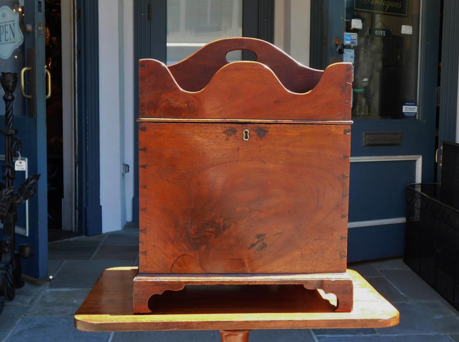 English Chippendale mahogany cellarette with a hinged scalloped compartmentalized lid, flanking brass side handles, interior lock with key, exposed dovetails, and resting on the original bracket feet. Late 18th Century.