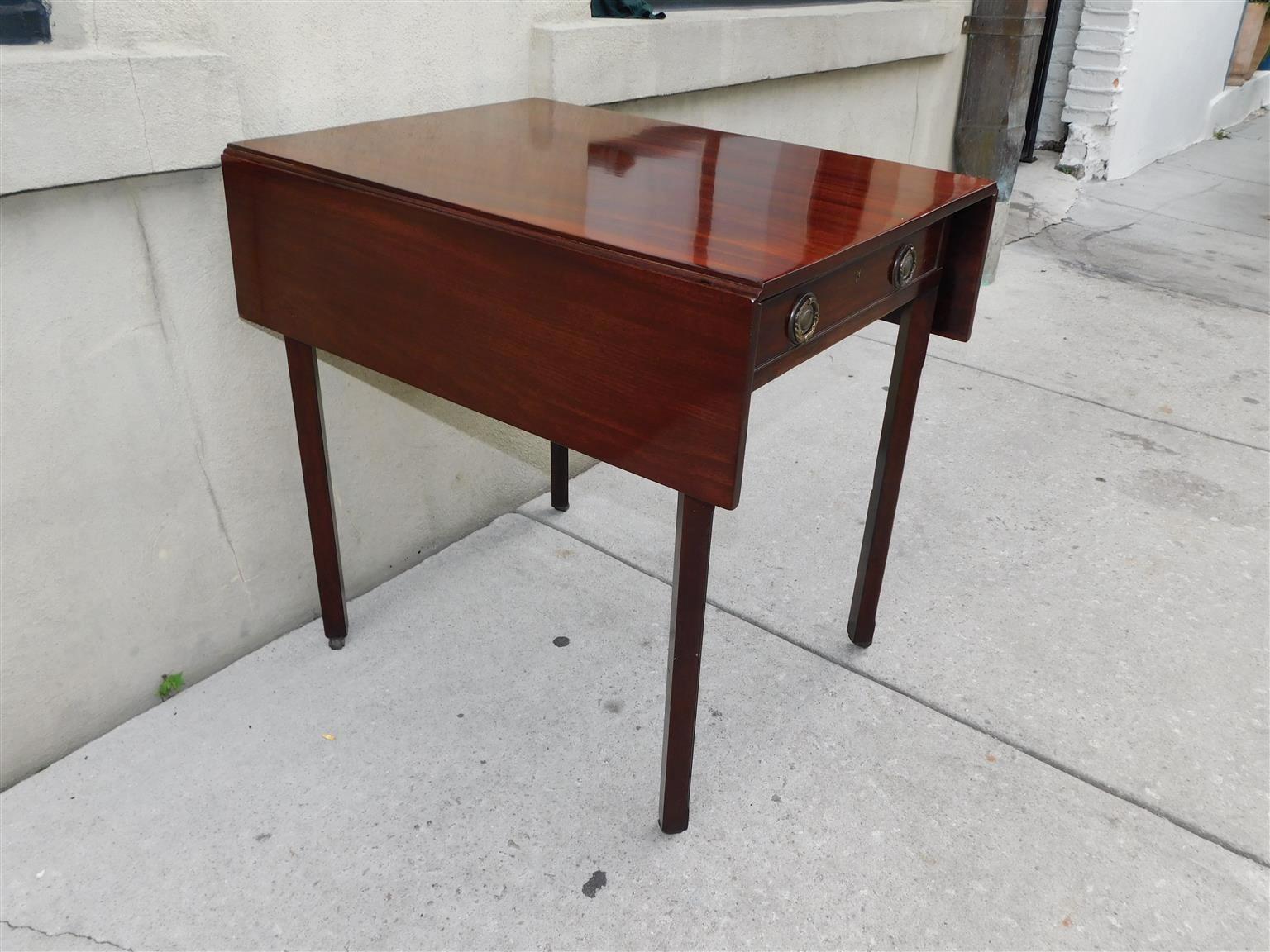 English Chippendale Mahogany drop leaf Pembroke table with a one board top, single drawer with original foliage brasses, central keyhole escutcheon  with interior lock, and resting on squared chamfered legs with the original leather barrel casters,