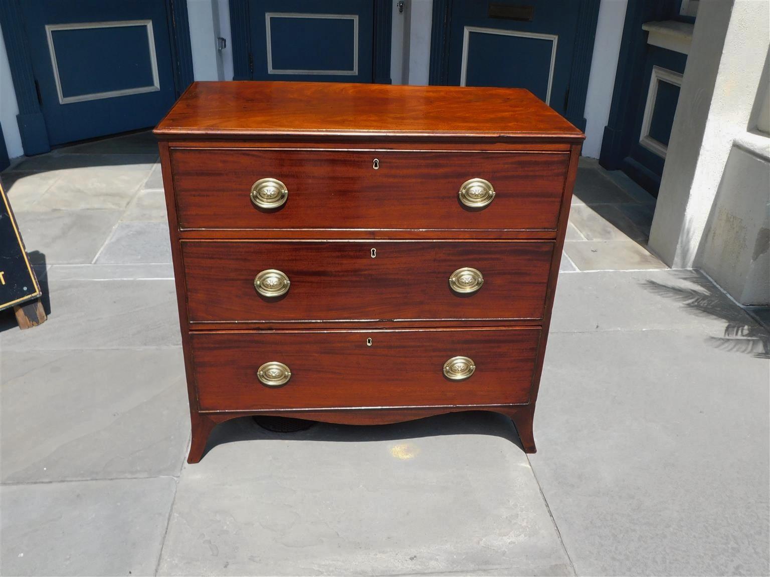 English Hepplewhite Mahogany graduated three drawer chest with a carved molded edge top, original brasses, escutcheons, interior locks, scalloped skirt, and resting on the original splayed feet. Late 18th century.