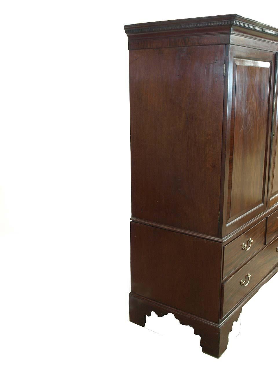 English mahogany Chippendale linen press, with removable cove cornice featuring dentil molding and vertical mahogany veneer, the doors with beautiful matching mahogany veneer raised panels that are cross banded in mahogany. The interior has six