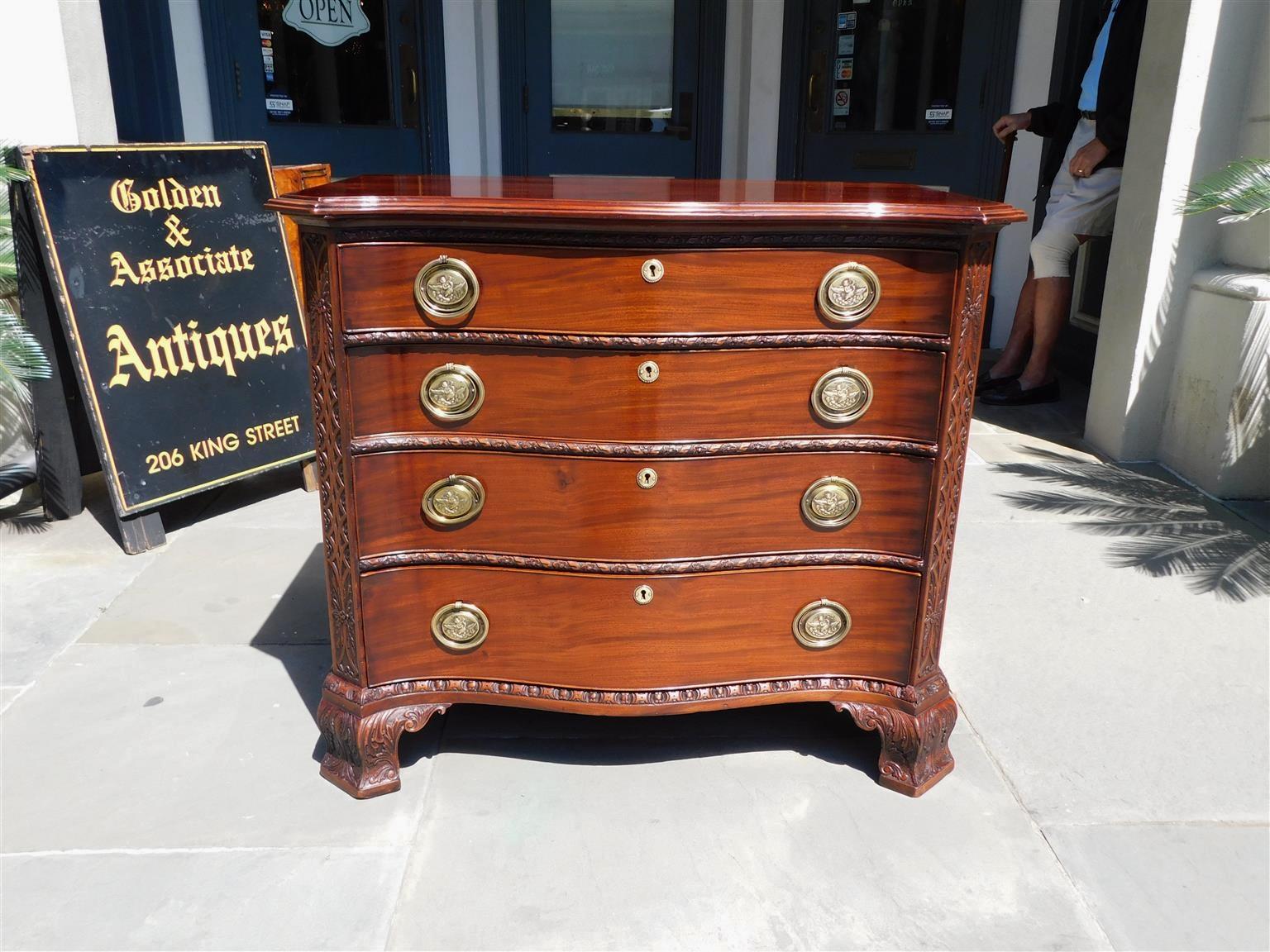 English Chippendale mahogany serpentine chest with a carved molded edge top, four graduated drawers, original cherub swan brass pulls, interior locks, and key escutcheons, carved foliate canted corners, and resting on the original acanthus carved