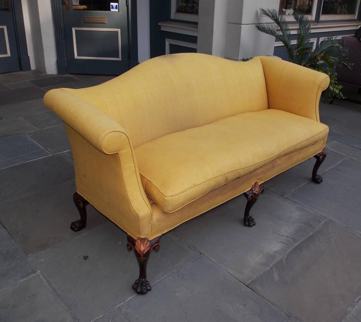 English Chippendale mahogany serpentine upholstered sofa with flanking scrolled arms, gilt carved shell with graduated bell flower motif, and terminating on the original hairy paw feet, Mid-18th century.