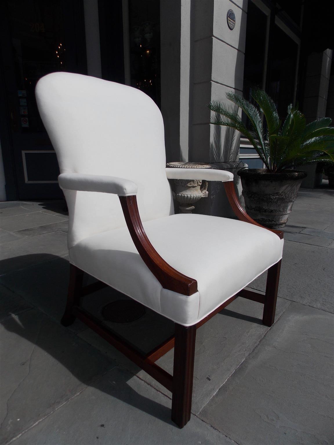 English Chippendale mahogany spoon back library chair with flanking scrolled fluted arms and resting on fluted squared legs, splayed rear legs with the original connecting stretchers. Chair is upholstered in white muslin with horse hair and cotton