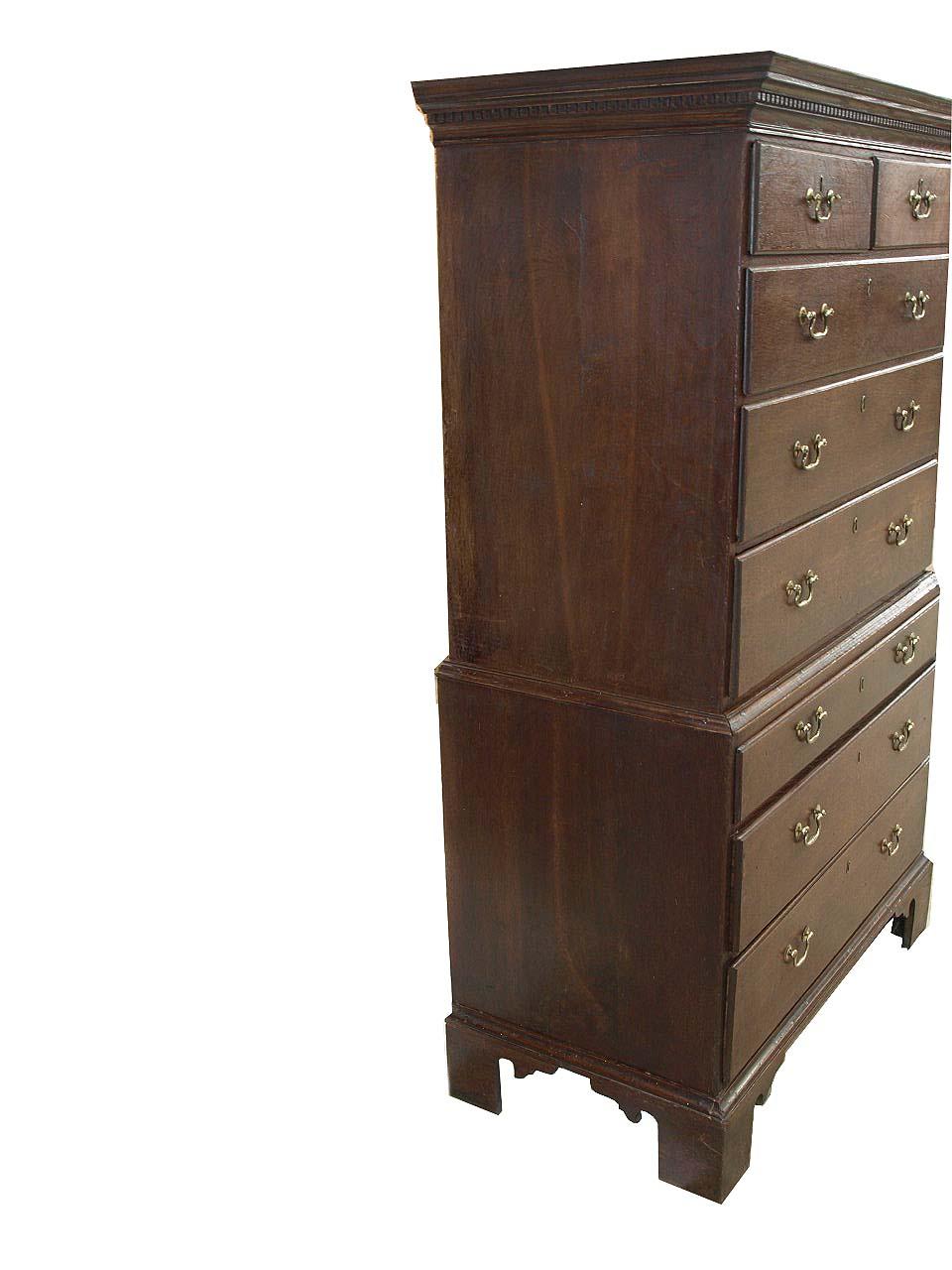 English Chippendale oak chest on chest, the cove cornice with dentil molding, the '' overlapping'' (as opposed to cock beaded) drawers retain their original swan neck pulls and raised brass insert escutcheons. The nicely shaped bracket feet are also