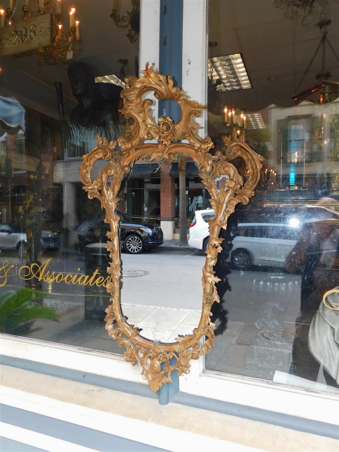 English Chippendale oval gilt wood & gesso floral cartouche wall mirror.  Mirror retains the original silvered glass and wood backing. Late 18th Century