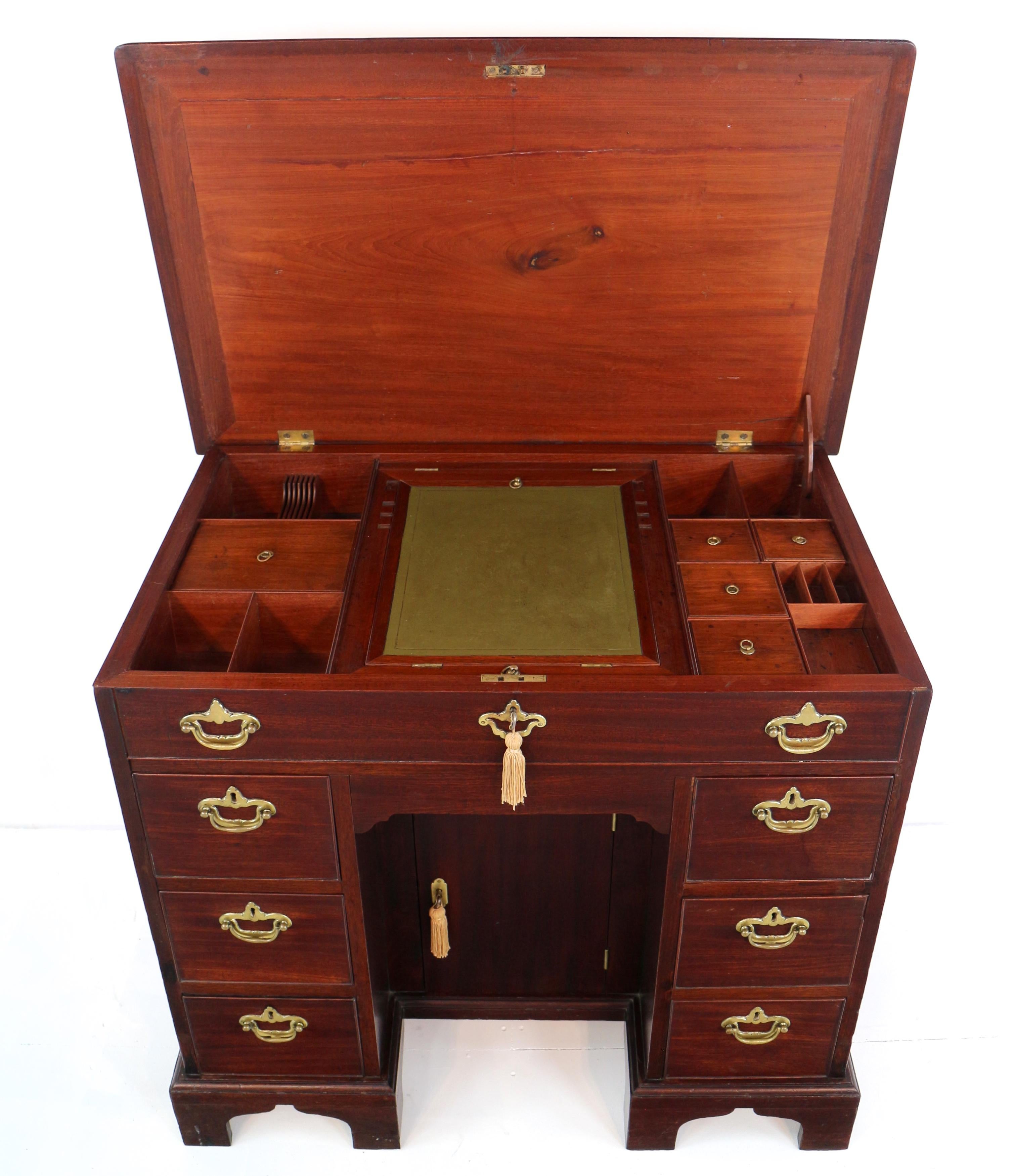 A good Chippendale period mid 18th century red walnut kneehole writing desk dressing table of small proportions and dating to circa 1740-50.  With a lift-up top featuring a fully fitted interior with a central ratcheted writing slope, lidded