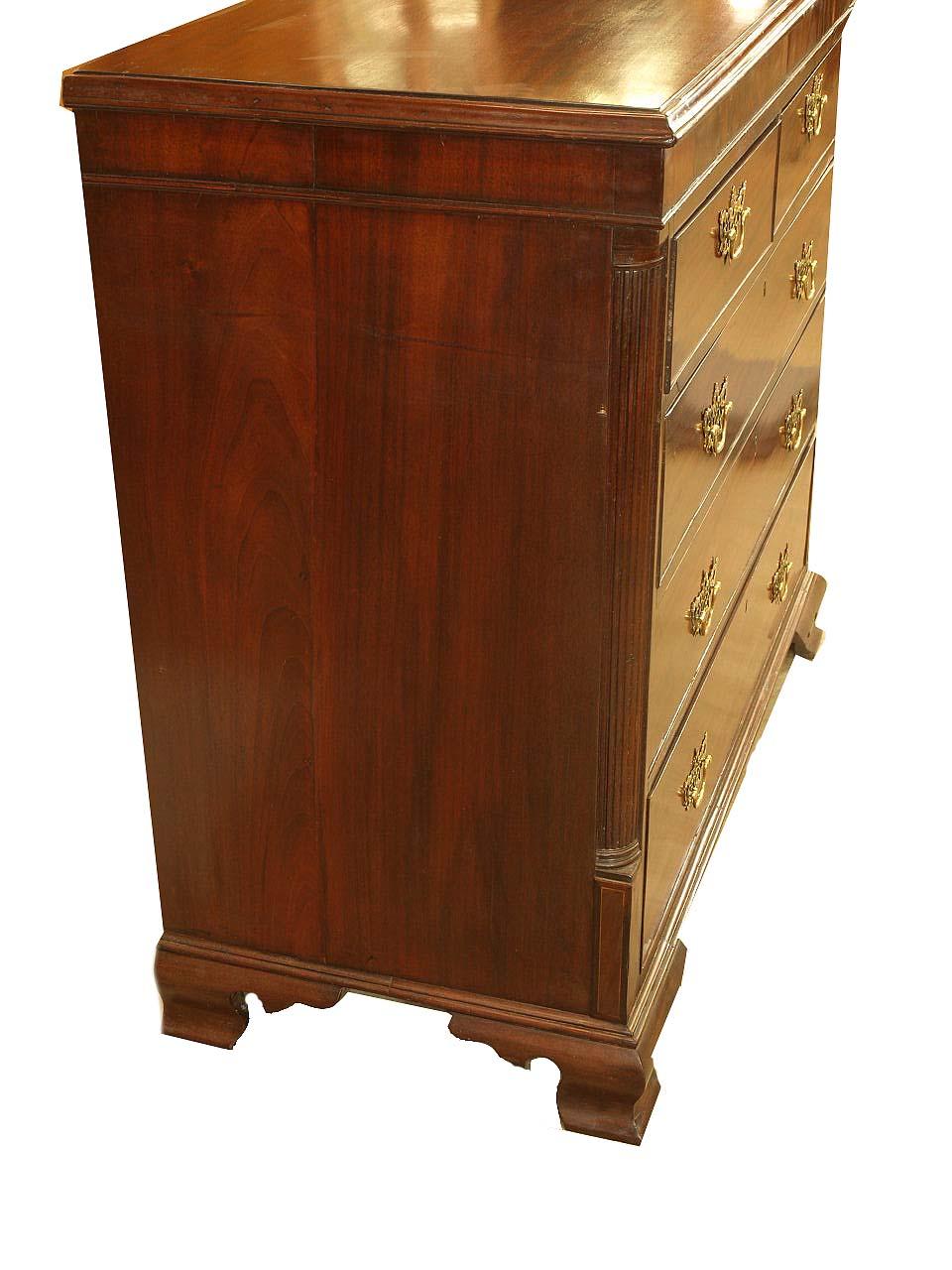English Chippendale chest, the two over three drawers with open fretwork brass pulls, reeded quarter column terminates with inlaid plinth. The chest rests on ogee bracket feet.