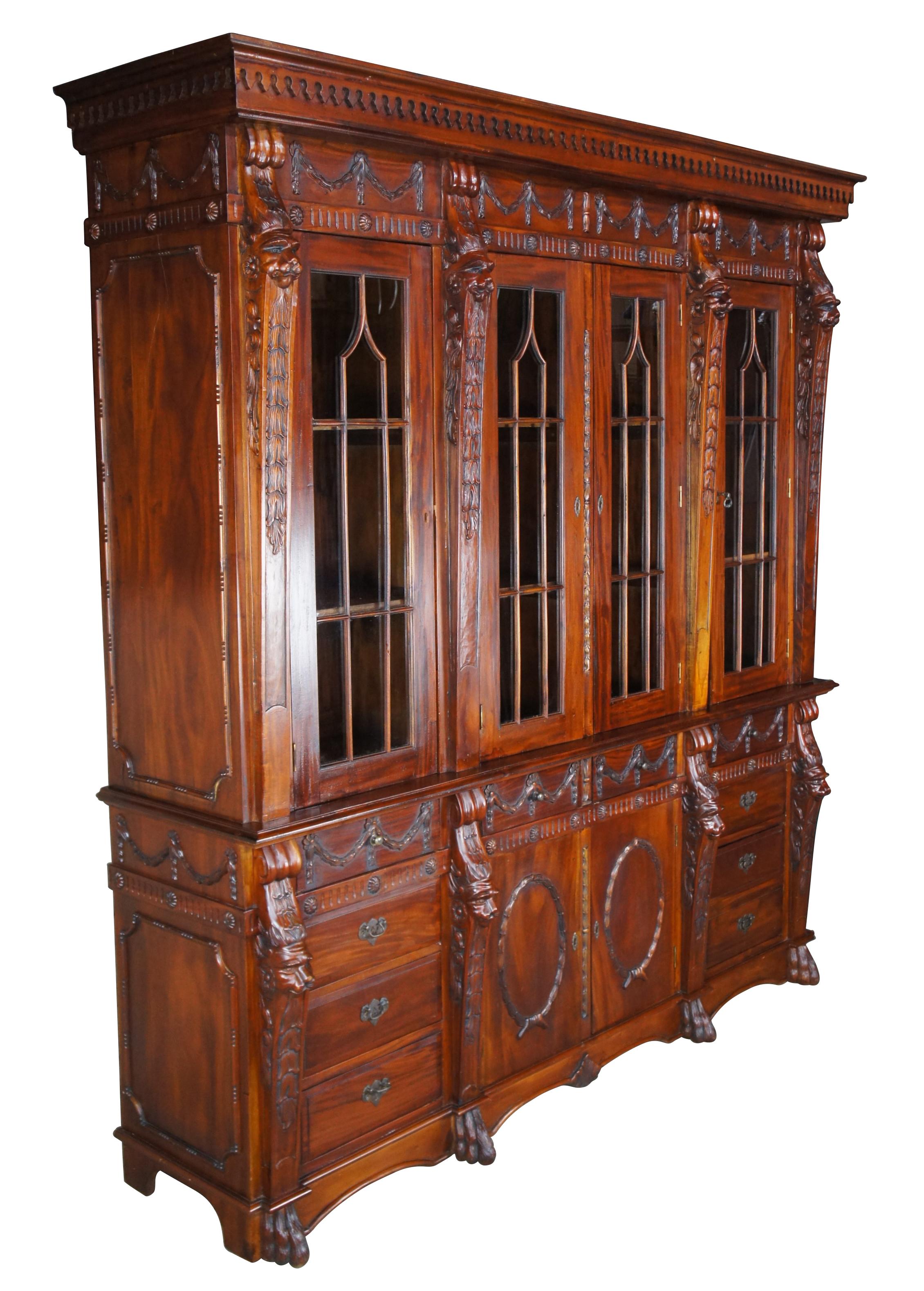 Vintage English Chippendale style solid mahogany carved china cabinet or cupboard.  Drawing inspiration from Neoclassicism and Empire design.  Made of mahogany featuring carved accents with sawtooth crown over Gothic fretwork doors divided by high