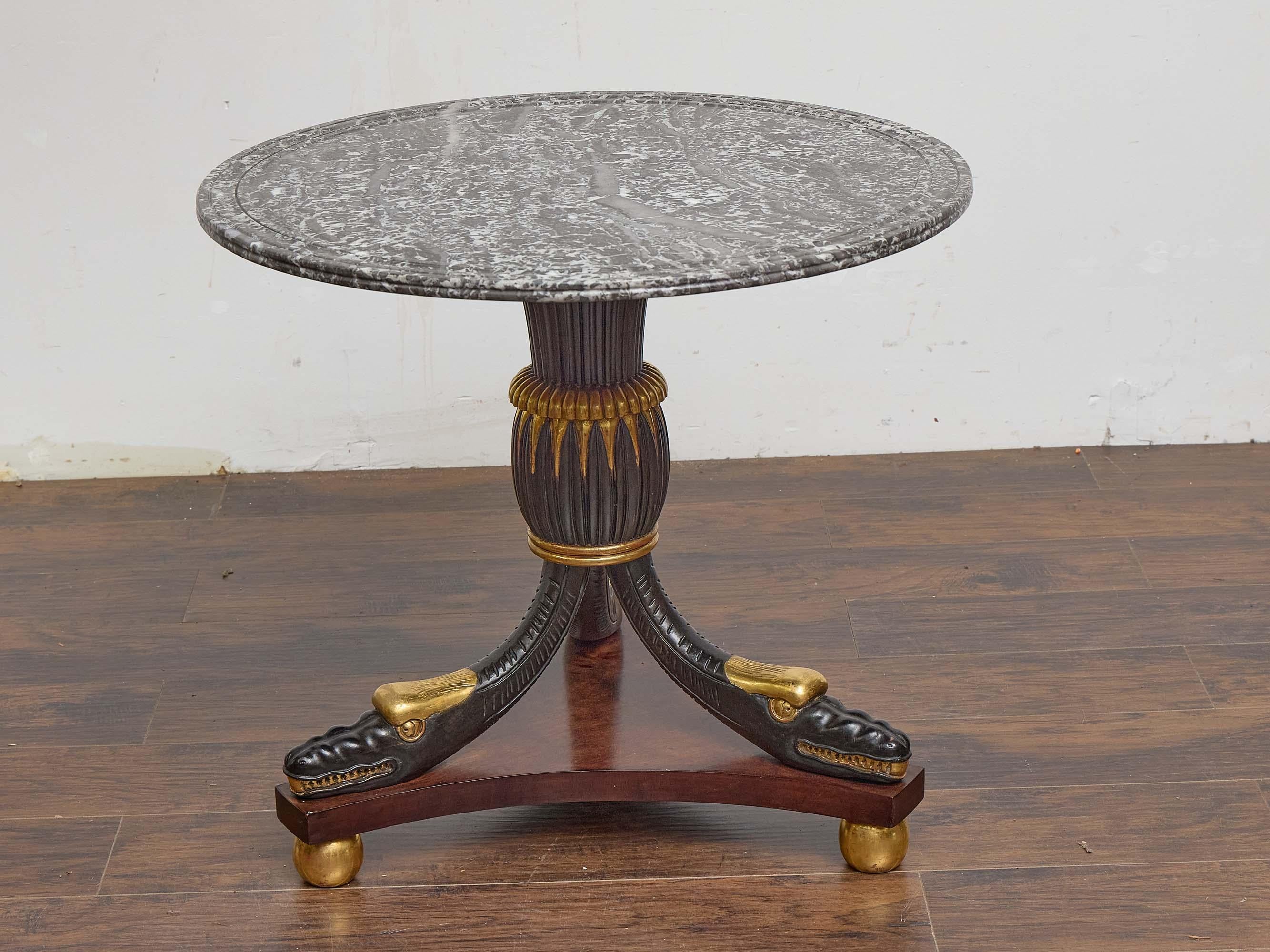 Dieser englische Tisch aus der Zeit um 1900 verbindet raffinierte Handwerkskunst mit kühnen dekorativen Details. Die kreisförmige Platte ist mit einem reich gemusterten grauen Marmor ausgestattet, dessen Oberfläche mit einer profilierten Kante