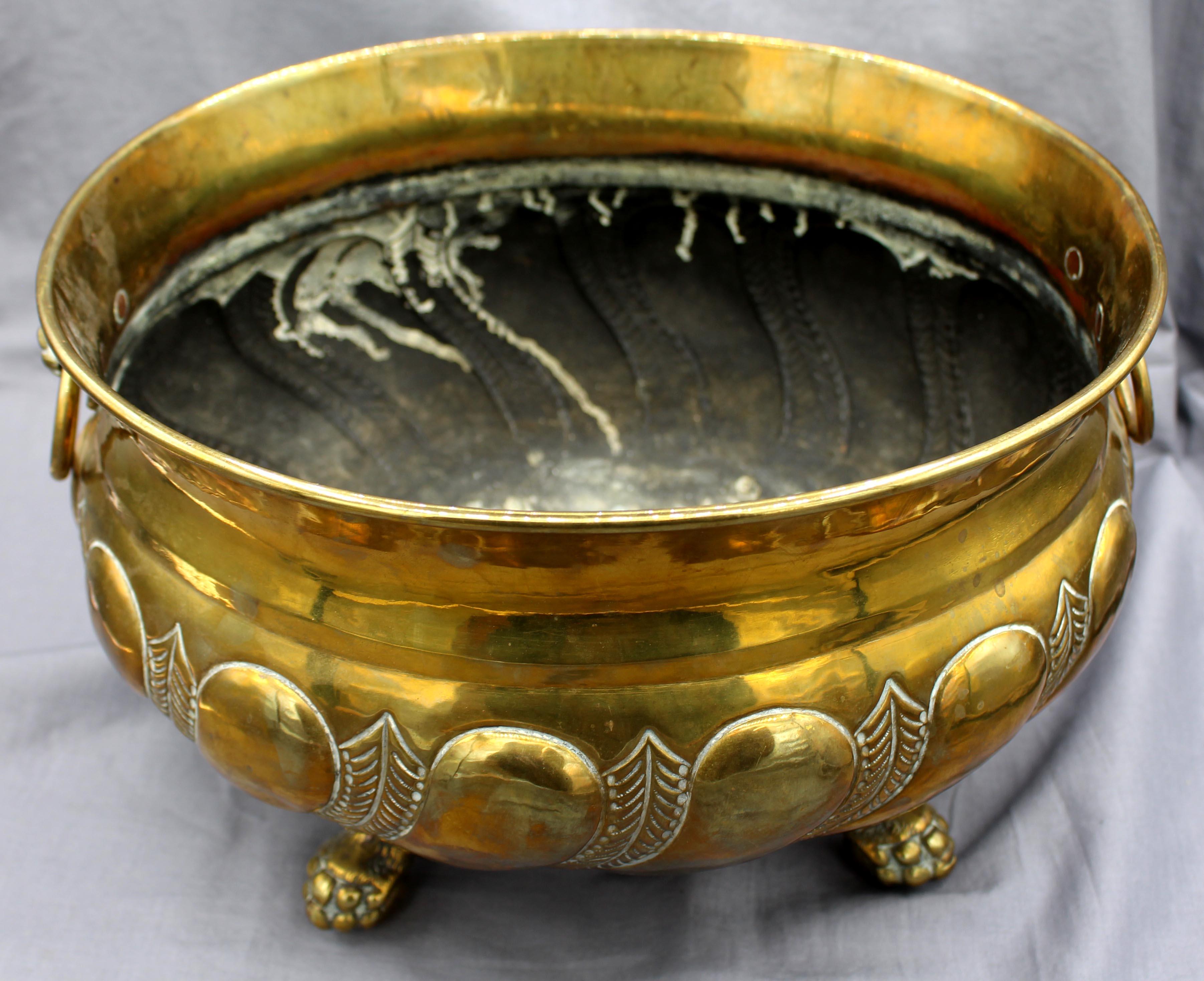 English circa 1900 oval brass jardiniere. Bold gadrooning & feather decoration, raised on finely detailed lion's paw feet with lion's mask ring handles.
13.5