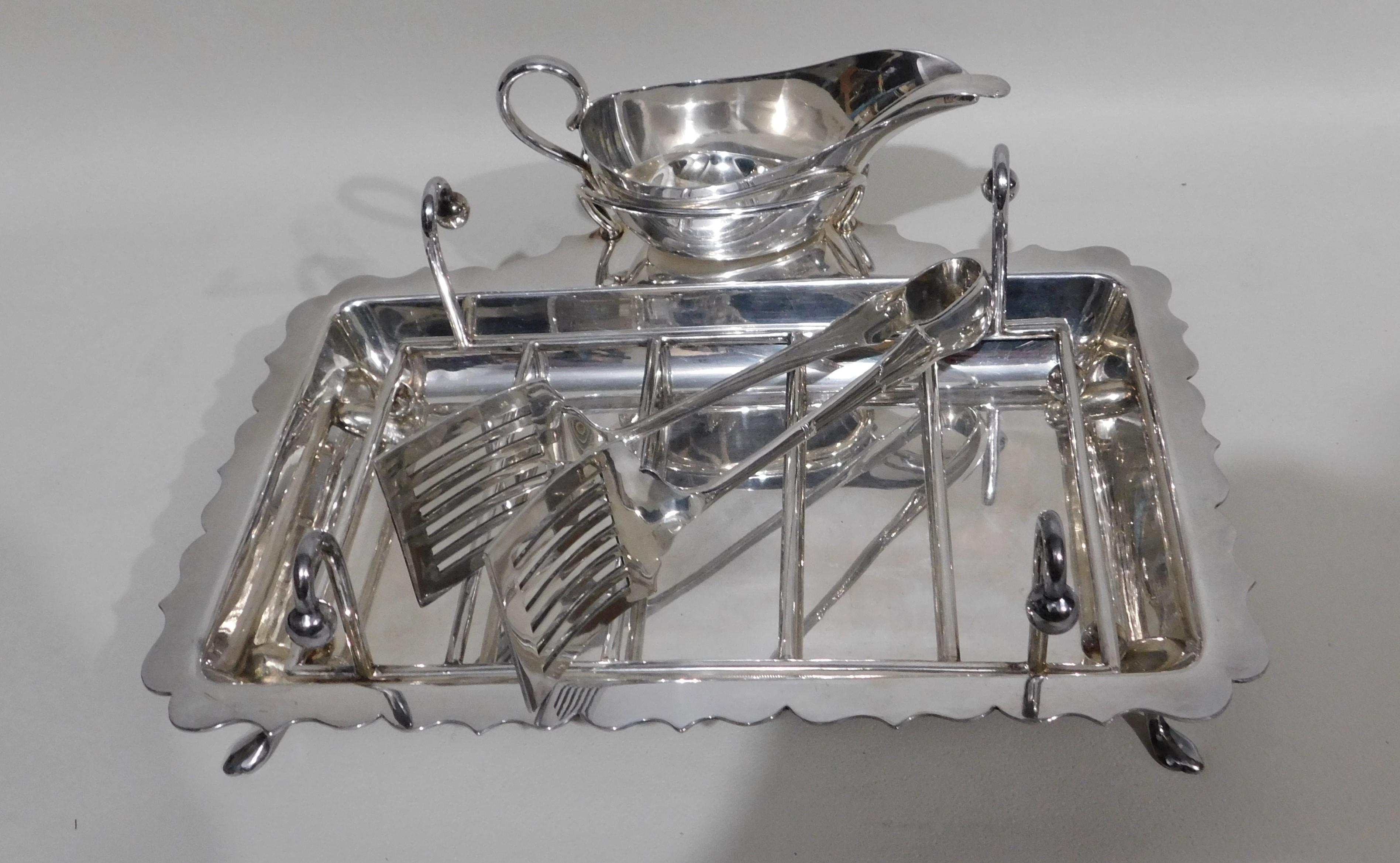 English five-piece silver plated asparagus serving set, having a plain rectangular body, a wire-work serving rack, a sauce boat sat in a frame with loop handle for hollandaise sauce or butter, a pair of asparagus server tongs, and all sitting on a