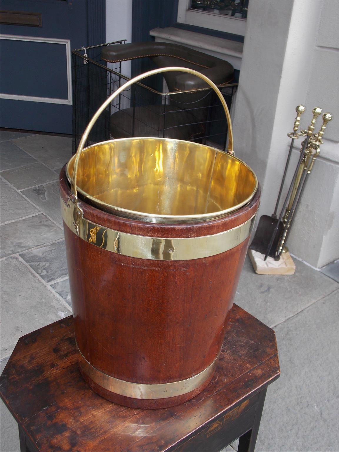 English circular form mahogany brass banded peat bucket with the original side mounted brass handle and removable interior liner, Early 19th century.