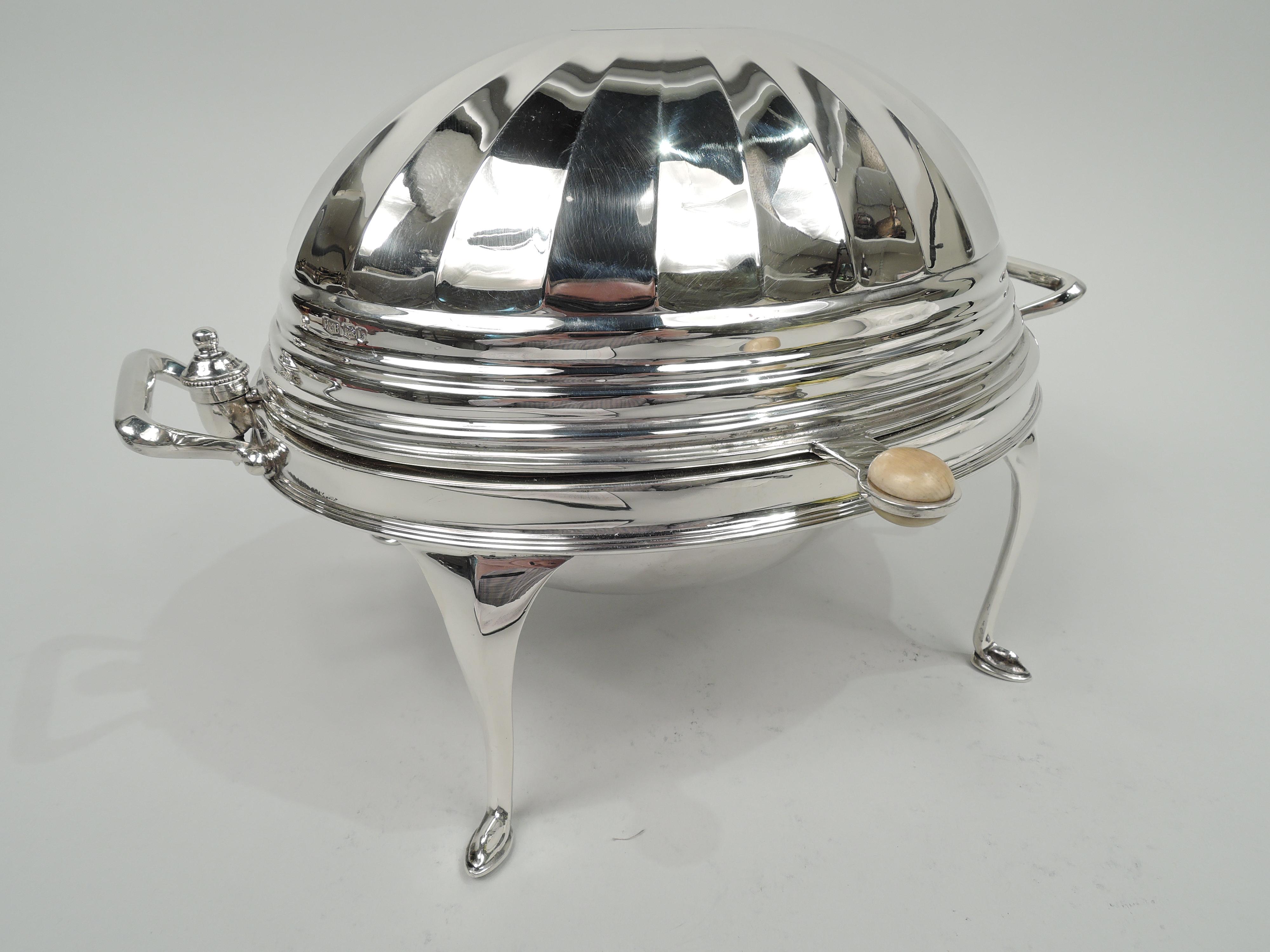 George V sterling silver bun warmer. Made by Roberts & Belk Ltd in Sheffield in 1927. Egg-form. Cover has flat oval top with radiating facets and lobed bands; hinges have vasiform mounts. Bracket end handles. Perpendicular tab has ring inset with